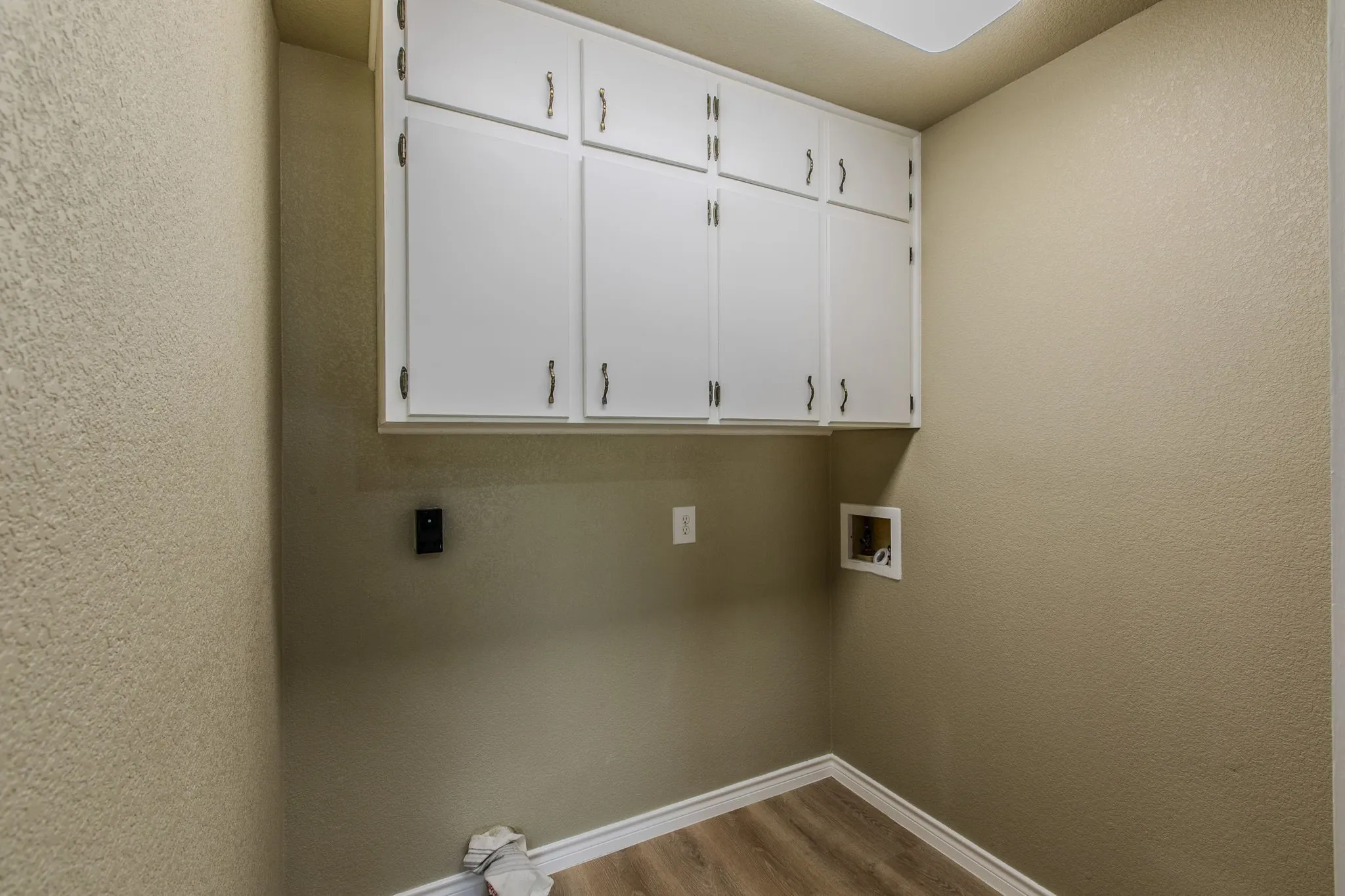 Laundry room with dark wood-style flooring, a textured wall, cabinet space, and hookup for a washing machine