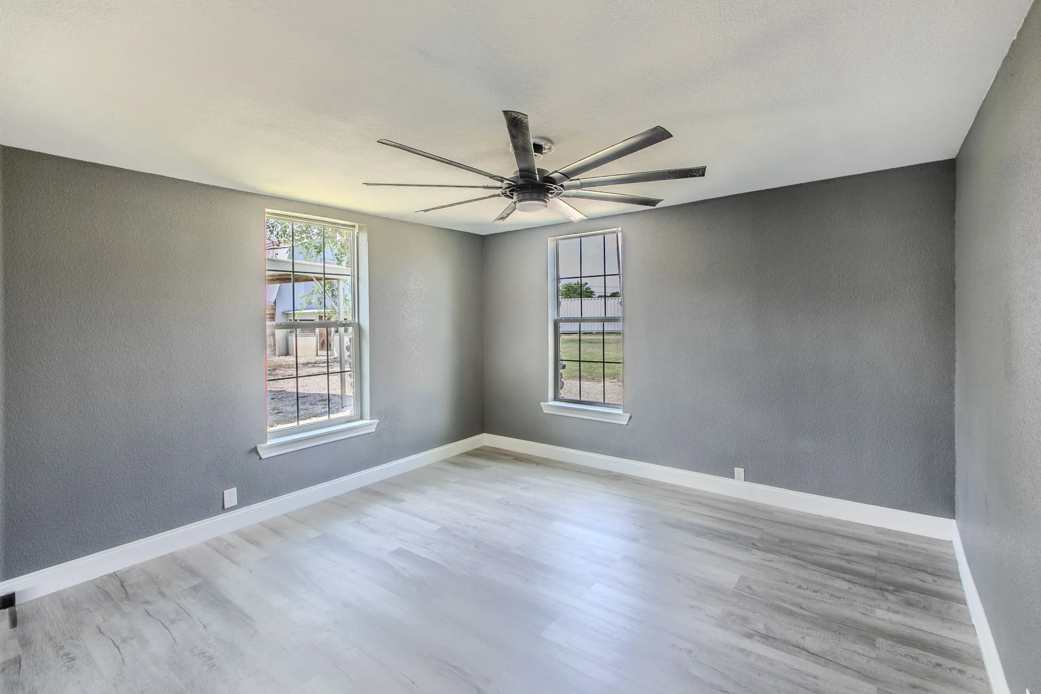 Spare room featuring a textured wall, light wood finished floors, and a ceiling fan