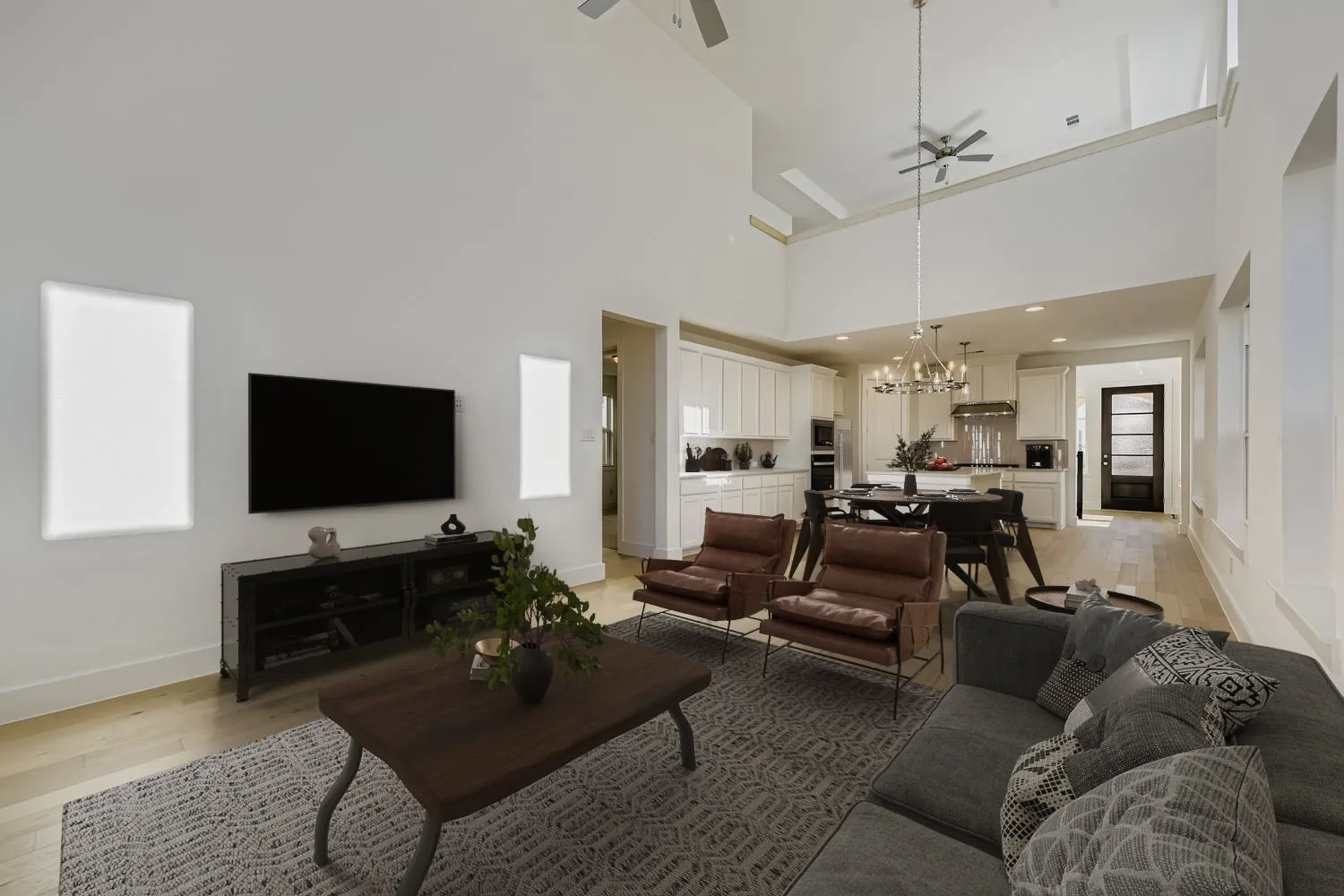 Virtually staged photo - Open-concept living space featuring soaring vaulted ceilings with skylights, hardwood flooring, and a neutral color palette