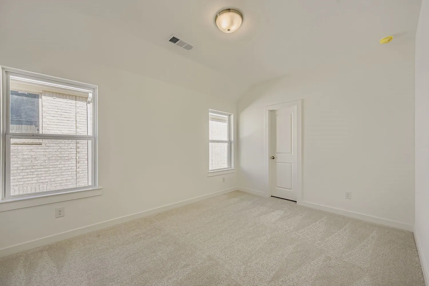 Empty room with light carpet and vaulted ceiling