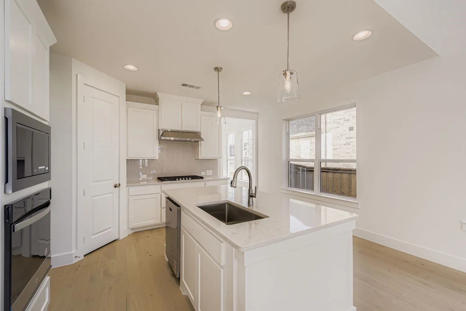 Kitchen featuring a kitchen island with sink, backsplash, light wood-style floors, appliances with stainless steel finishes, and recessed lighting