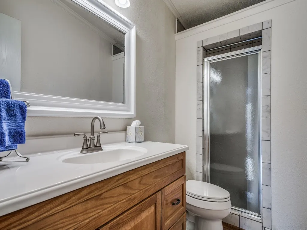 Full bath with a stall shower, vanity, a textured wall, and ornamental molding
