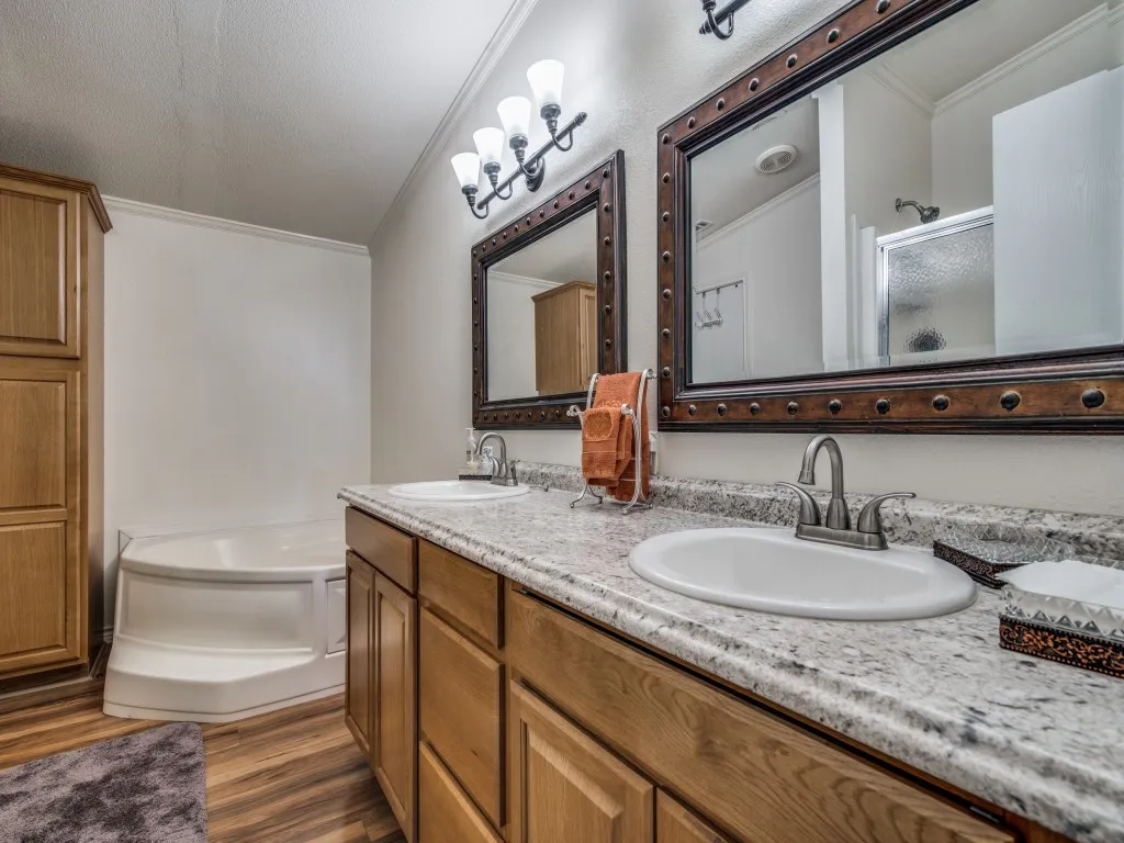 Bathroom featuring ornamental molding, double vanity, dark wood finished floors, a stall shower, and a bath