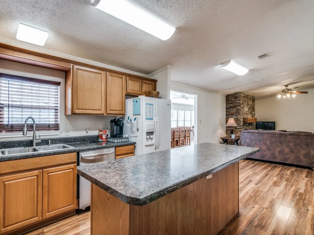Kitchen with a kitchen island, dark countertops, brown cabinets, light wood-type flooring, and ornamental molding