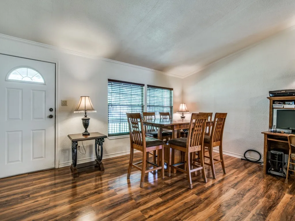 Dining space with a textured wall, wood finished floors, and crown molding