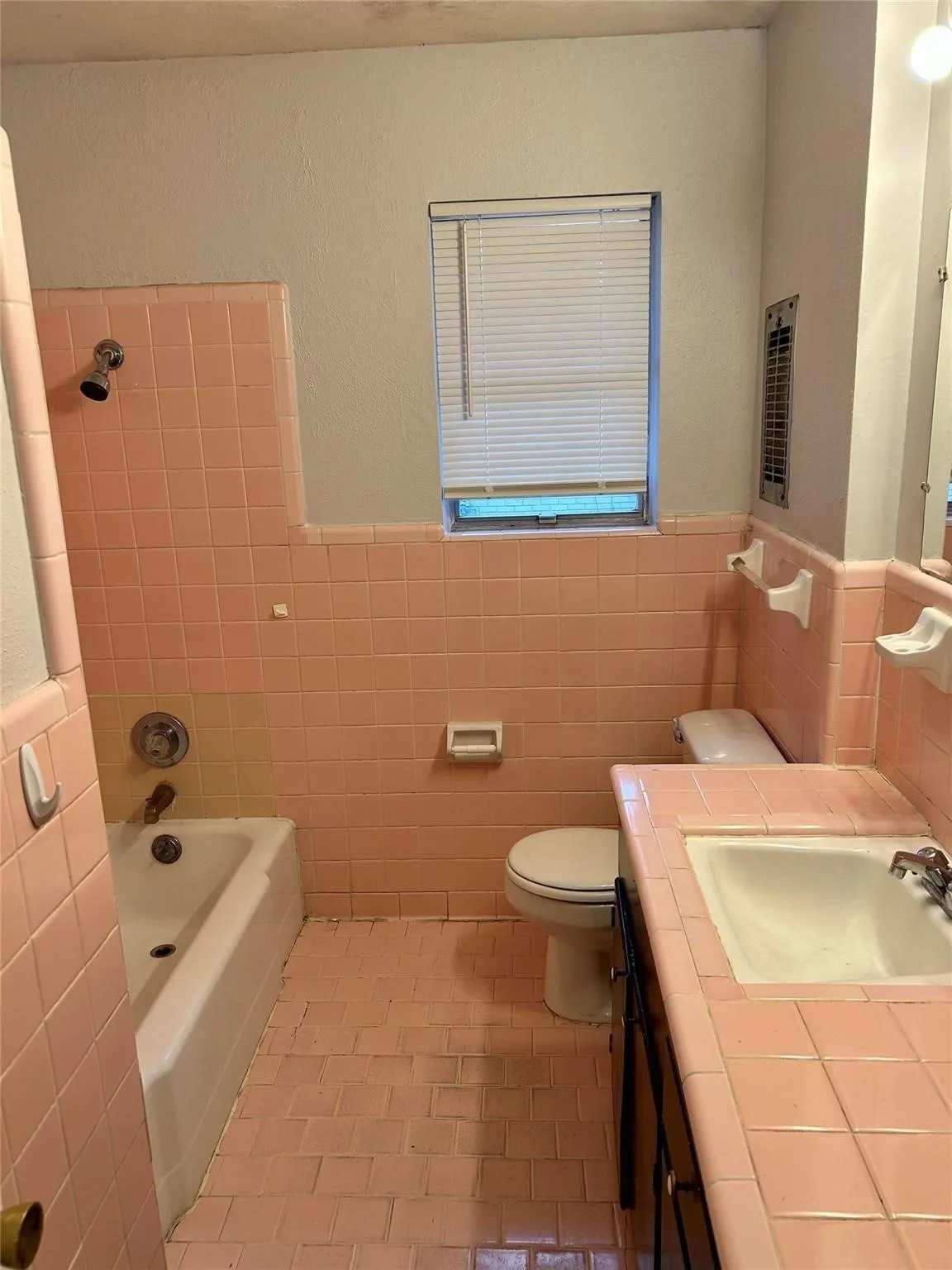 Bathroom with light tile patterned flooring, vanity, tile walls, wainscoting, and shower / washtub combination