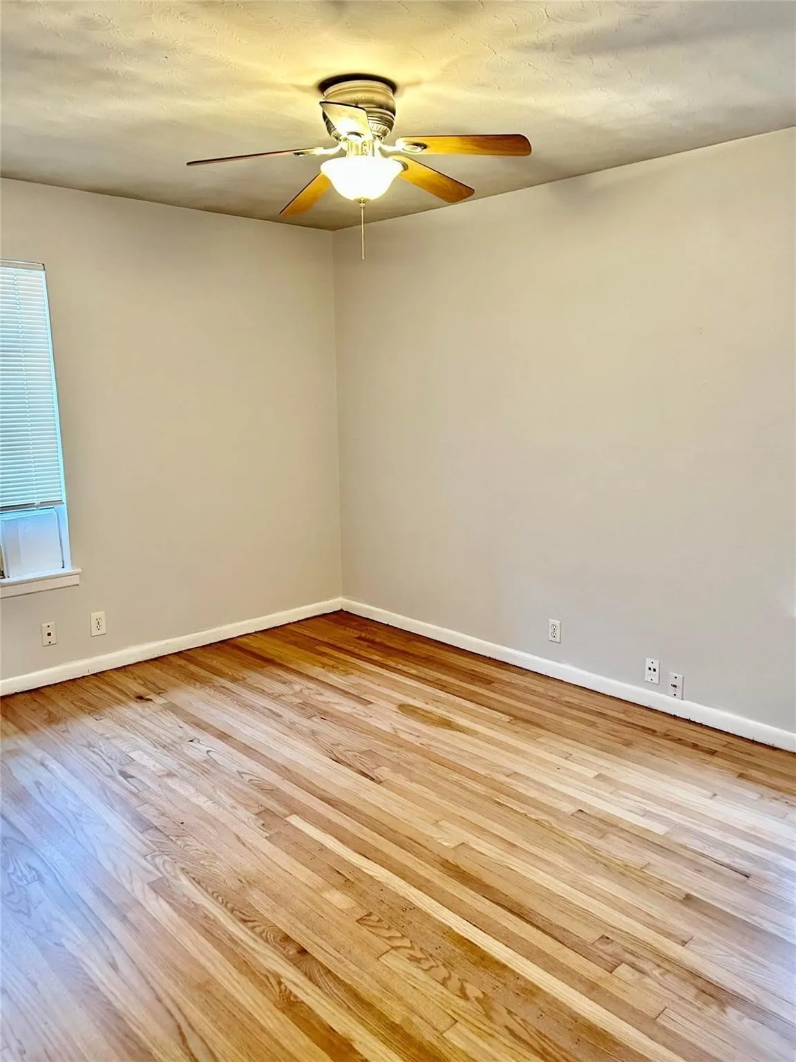Empty room featuring light wood-style flooring, ceiling fan, and a textured ceiling