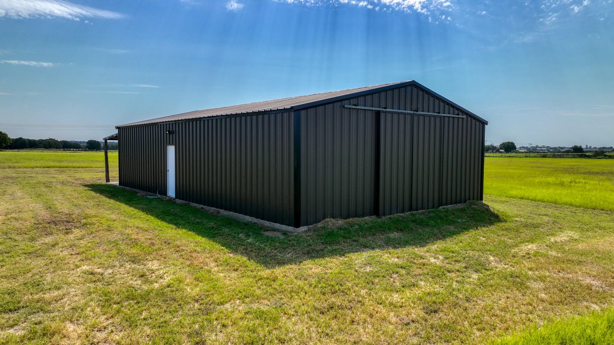 View of pole building with a lawn and a view of rural / pastoral area