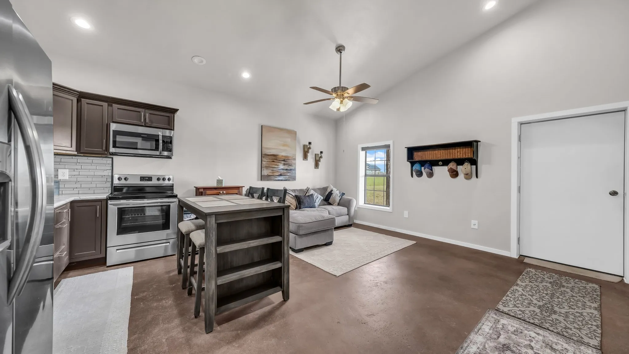 Living room featuring vaulted ceiling, concrete floors, a ceiling fan, and recessed lighting
