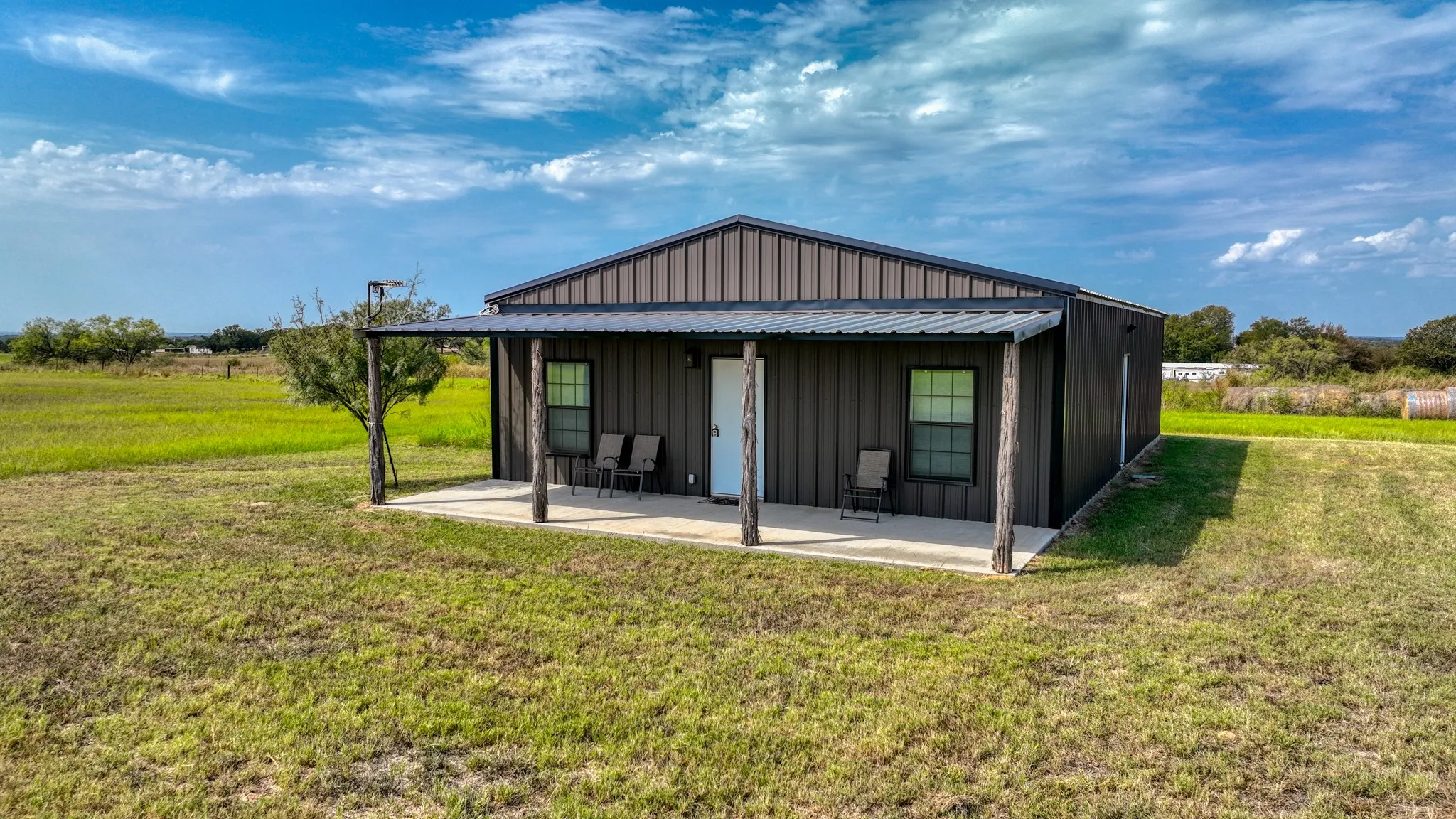 Rear view of property with board and batten siding, a lawn, and covered porch