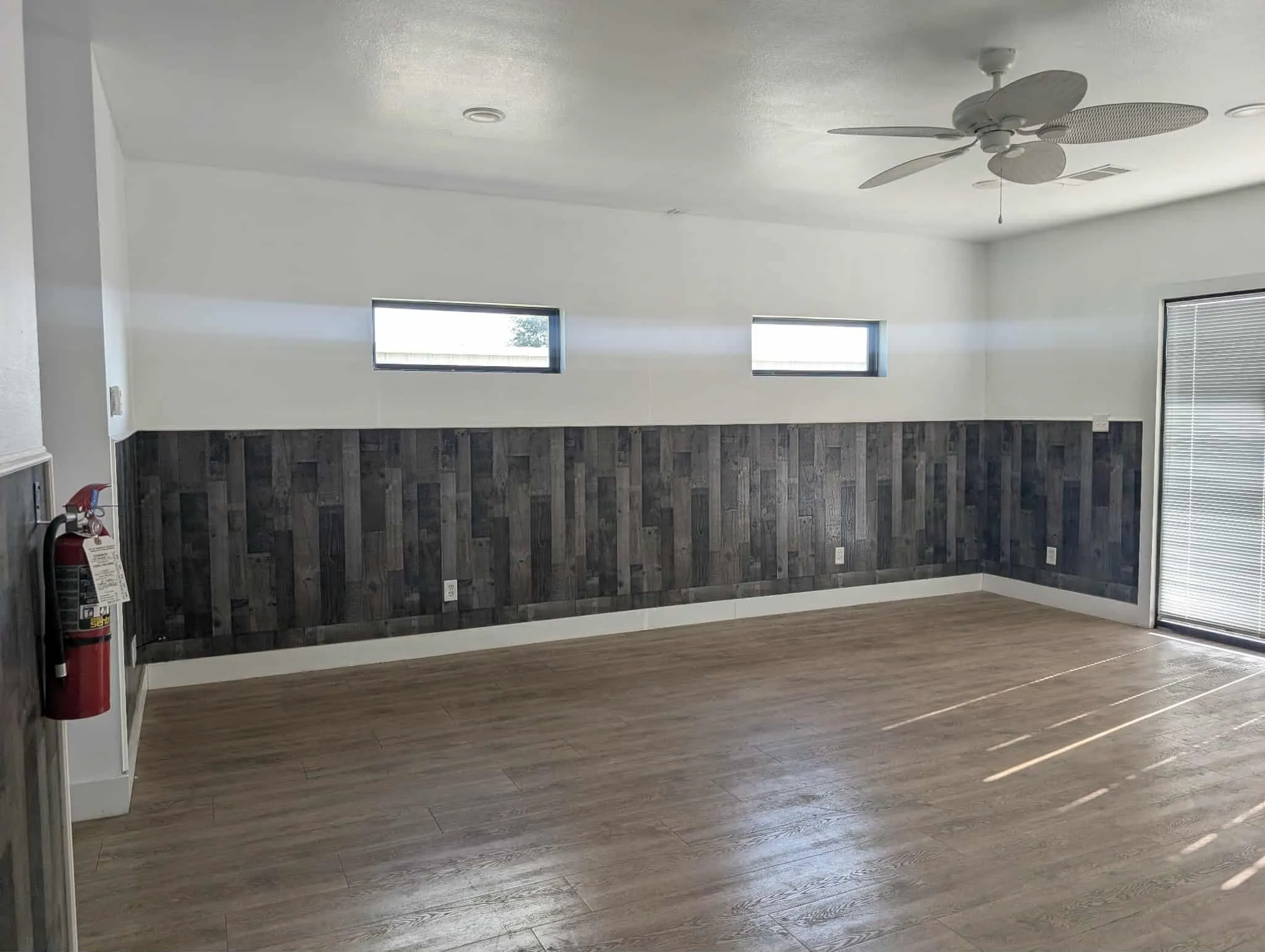 Spare room with wood finished floors, ceiling fan, a wainscoted wall, wooden walls, and a textured ceiling