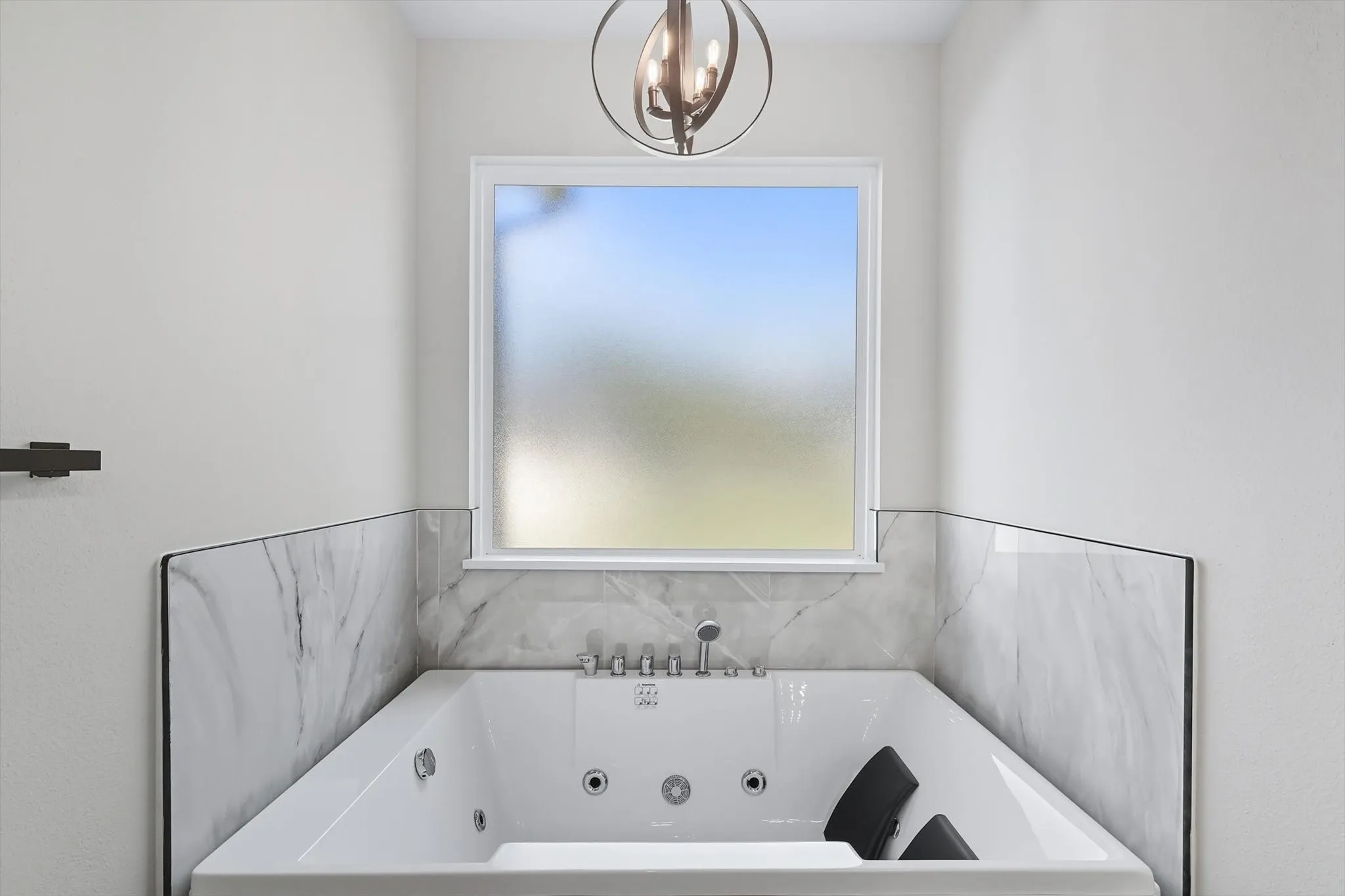 Bathroom featuring a tub with jets and a chandelier