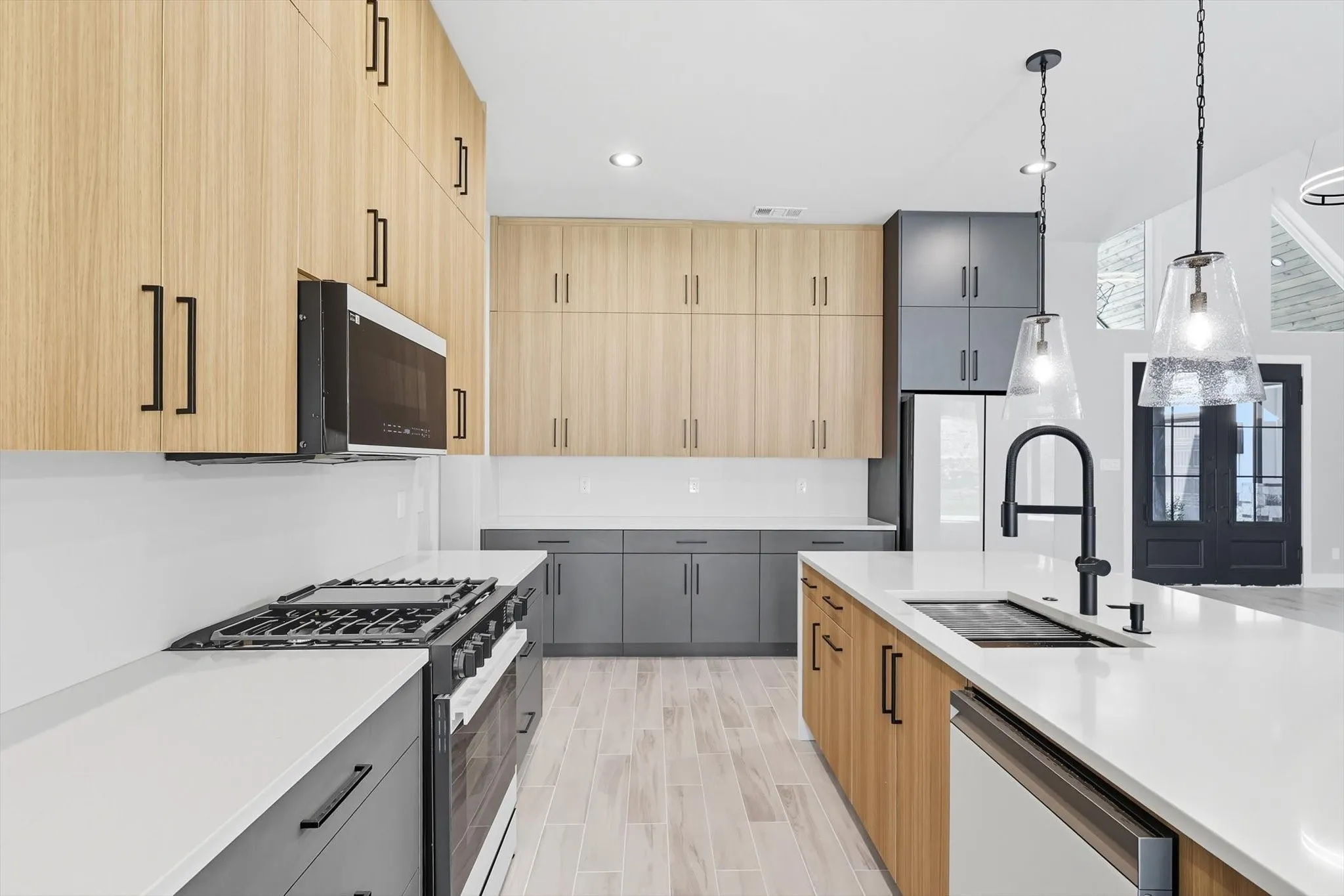 Kitchen with light brown cabinets, hanging light fixtures, appliances with stainless steel finishes, recessed lighting, and modern cabinets