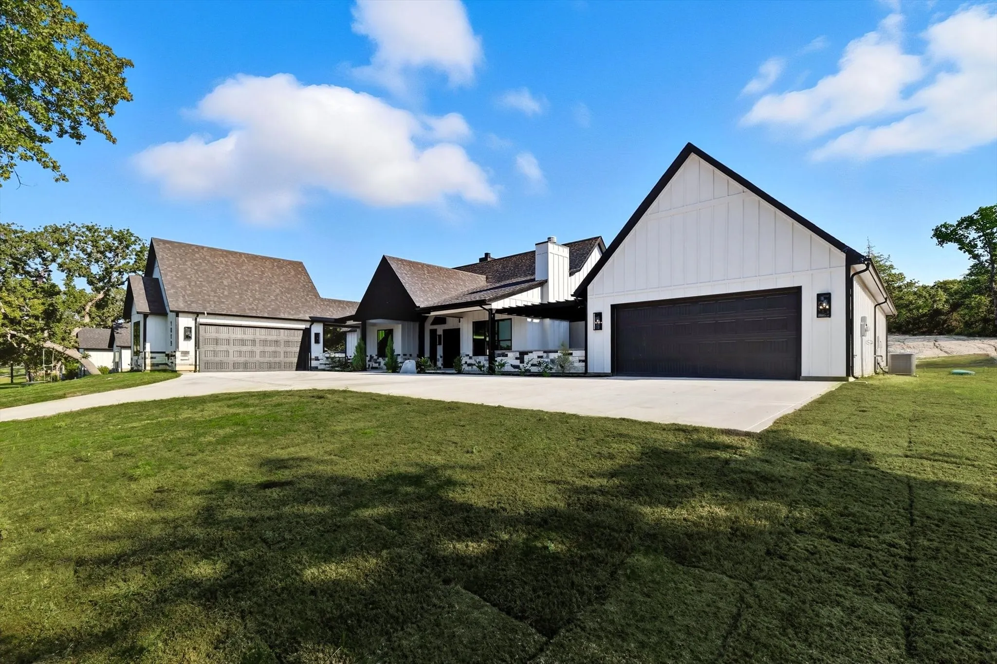 Modern inspired farmhouse featuring board and batten siding, a front lawn, driveway, and a garage