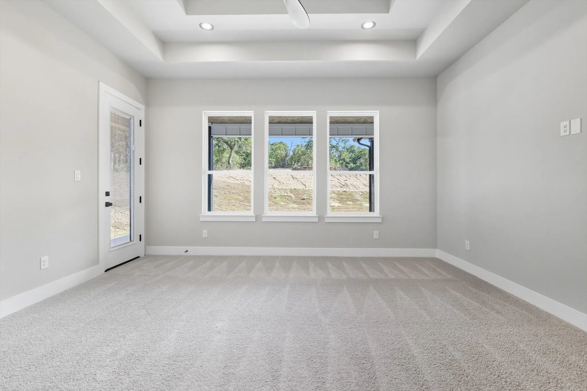 Unfurnished room with a raised ceiling, light colored carpet, and recessed lighting