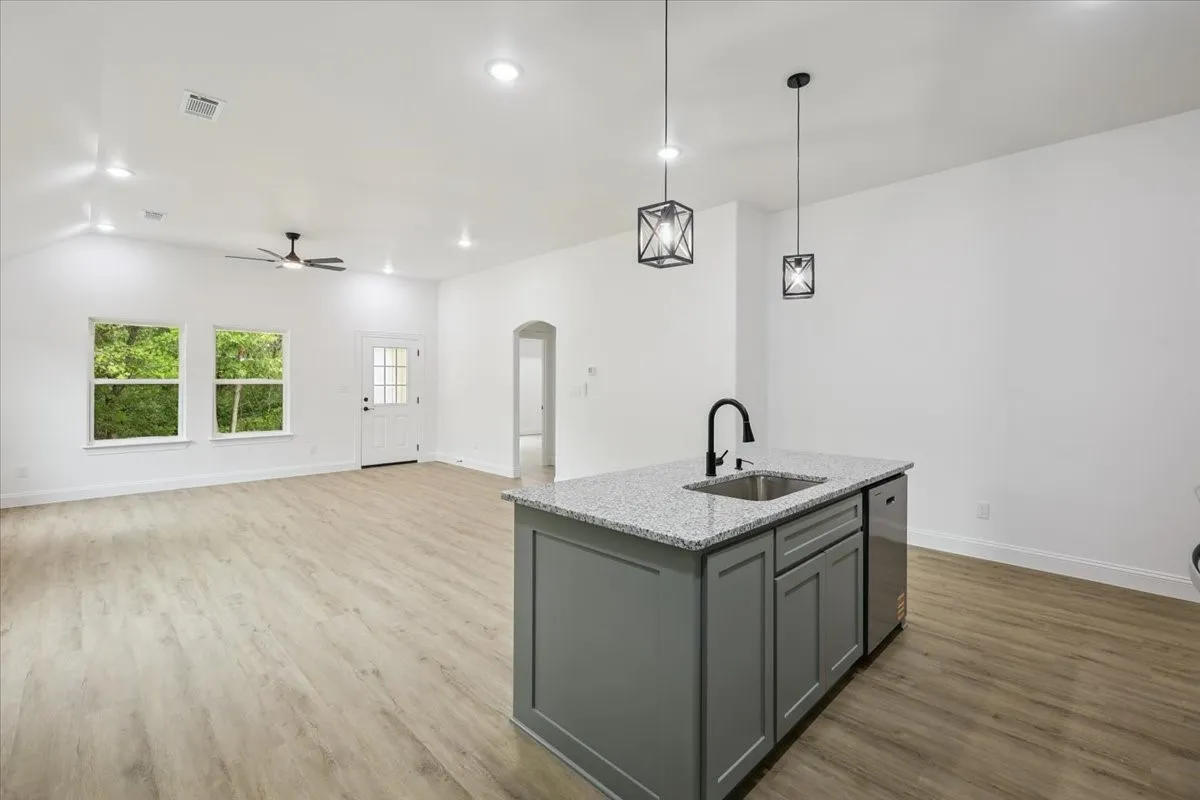 Kitchen featuring gray cabinets, arched walkways, pendant lighting, light stone counters, and light wood-type flooring