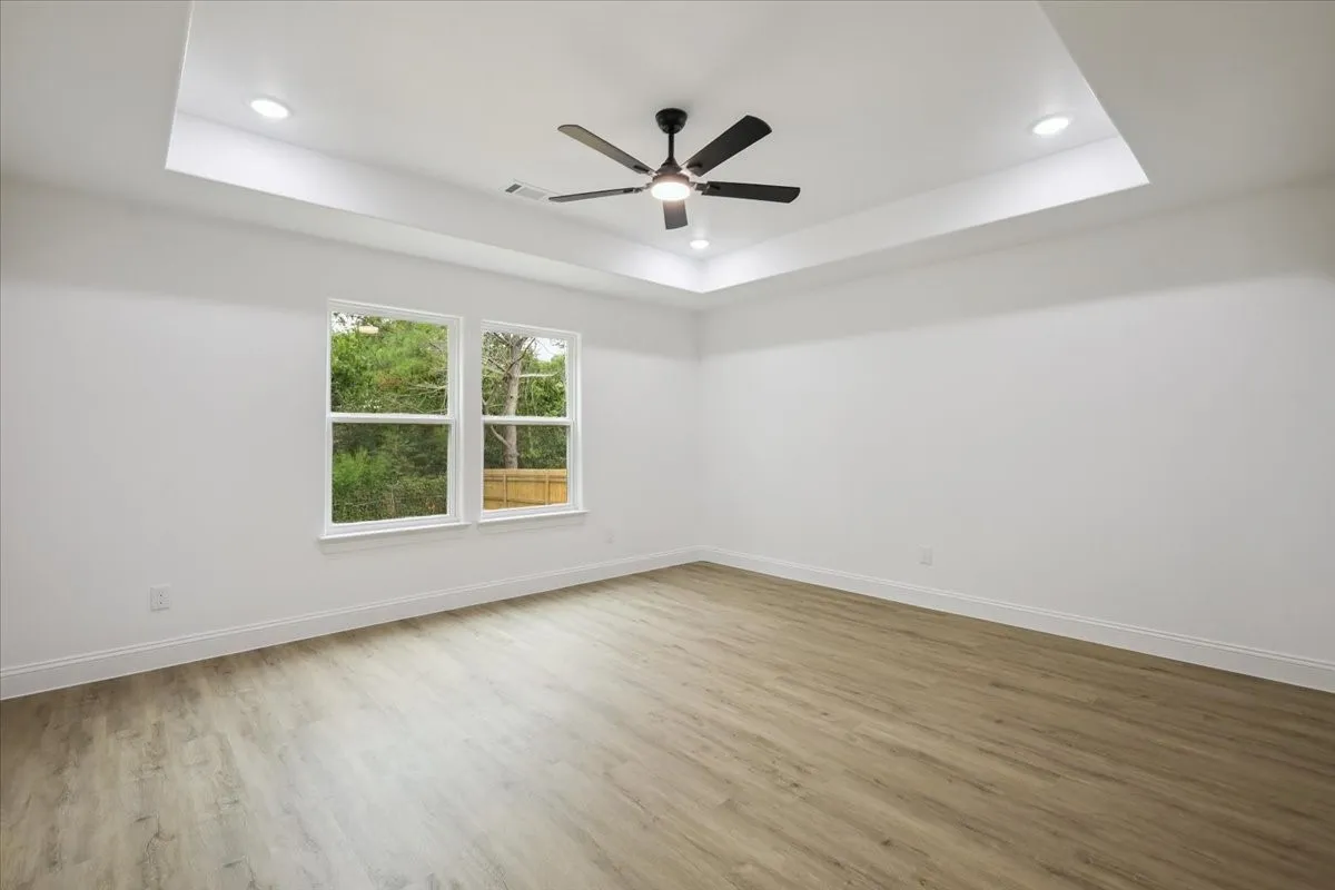 Unfurnished room with a tray ceiling, light wood-style floors, recessed lighting, and a ceiling fan
