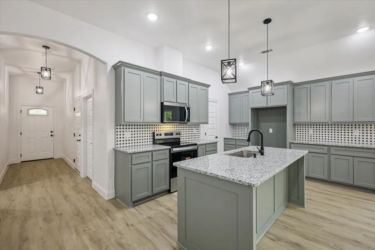 Kitchen with gray cabinets, backsplash, stainless steel appliances, and recessed lighting