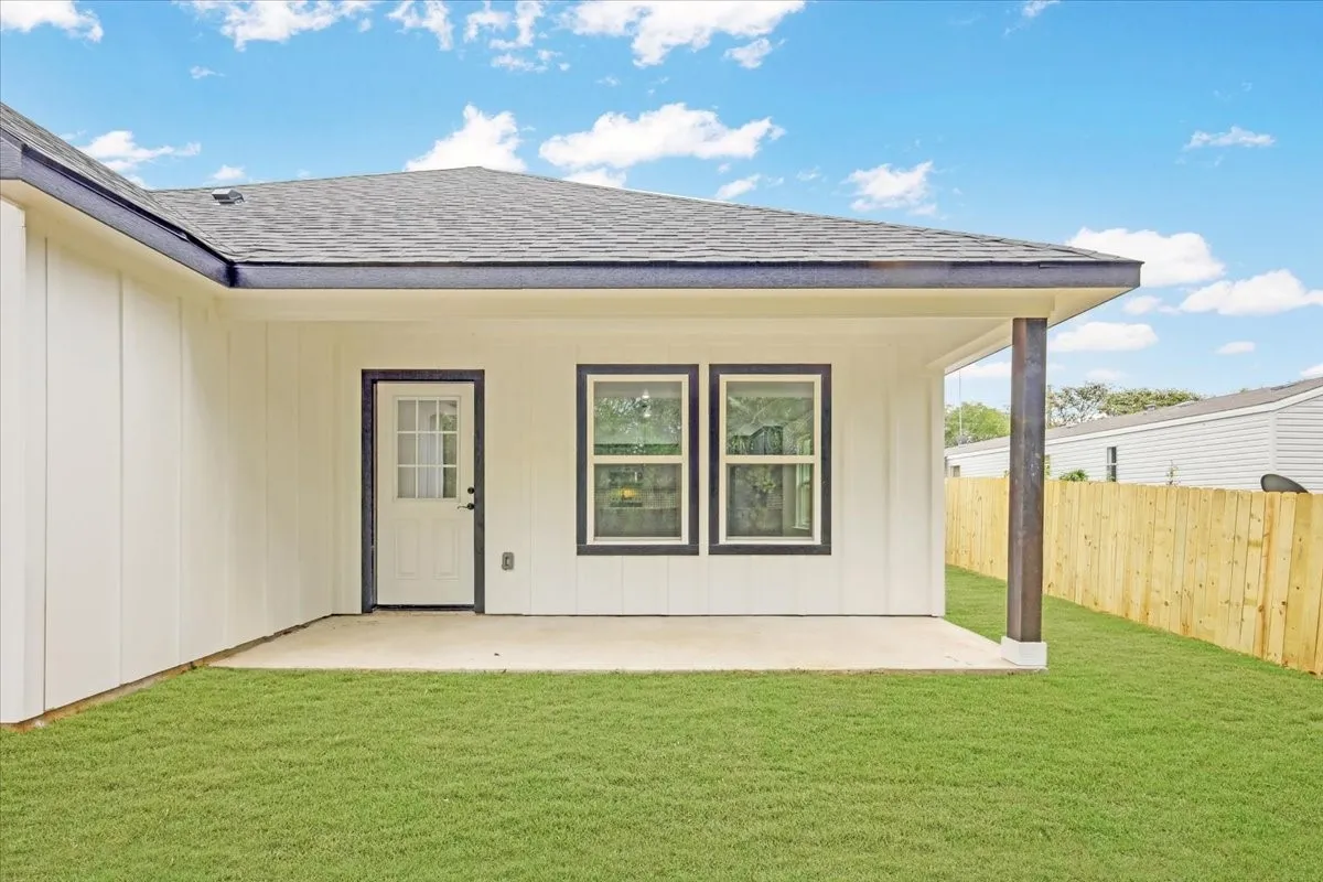 Doorway to property with a shingled roof and a patio area