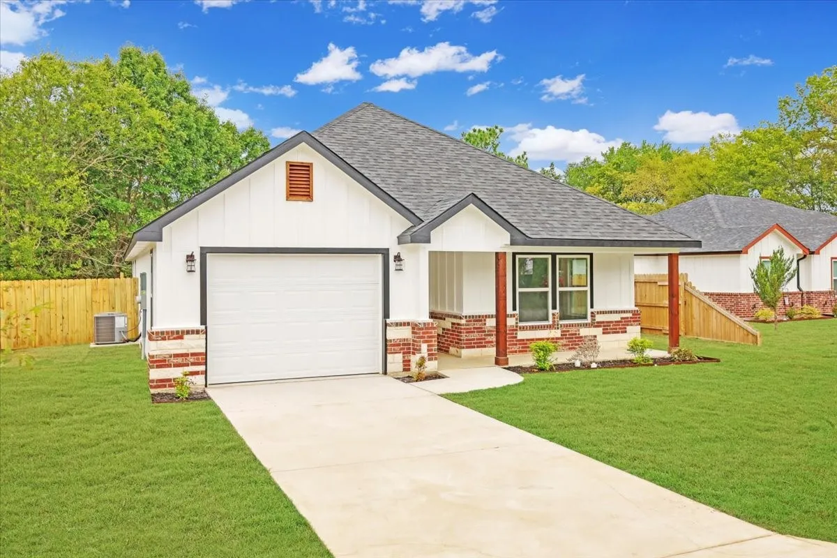 View of front of house with roof with shingles, brick siding, covered porch, and concrete driveway