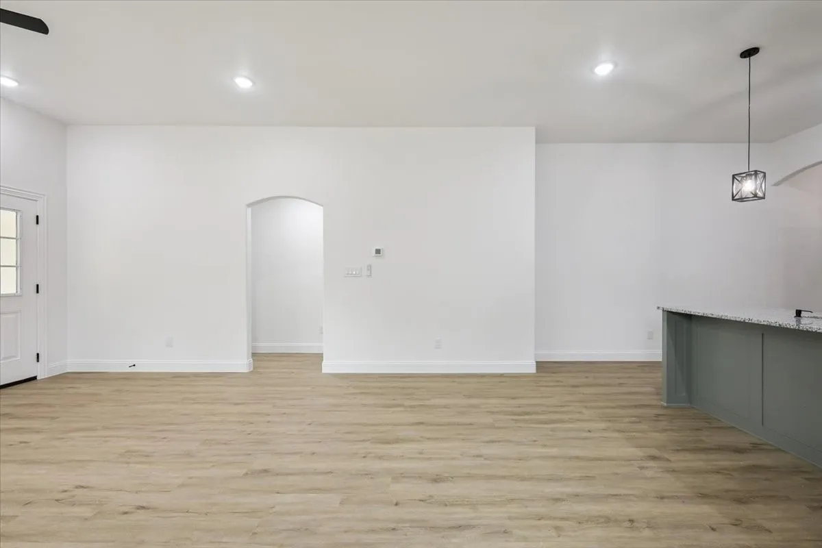 Unfurnished living room with light wood-style floors, recessed lighting, and arched walkways