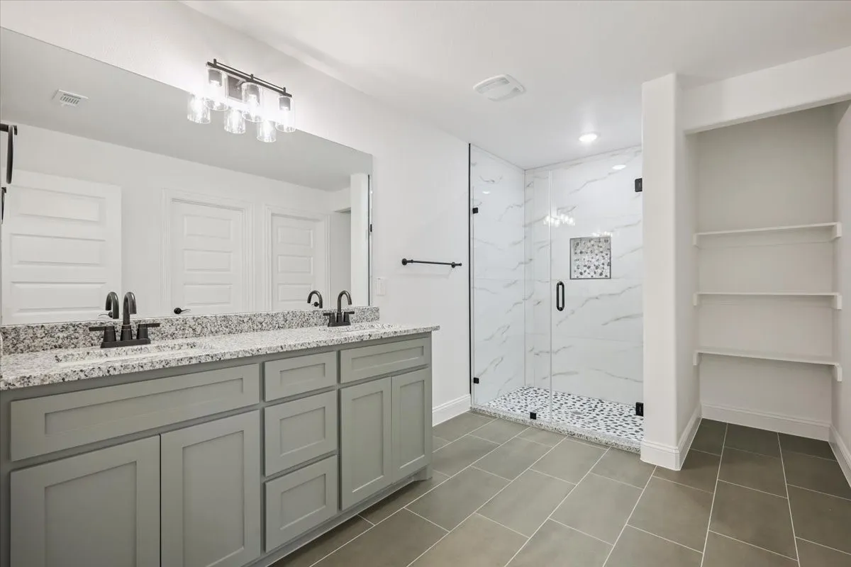 Bathroom featuring a marble finish shower, double vanity, dark tile patterned floors, recessed lighting, and a closet