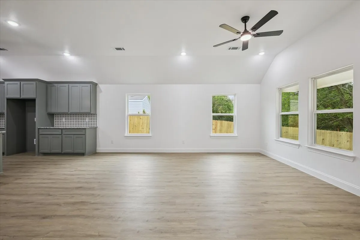 Unfurnished living room featuring light wood-style floors, plenty of natural light, recessed lighting, vaulted ceiling, and a ceiling fan