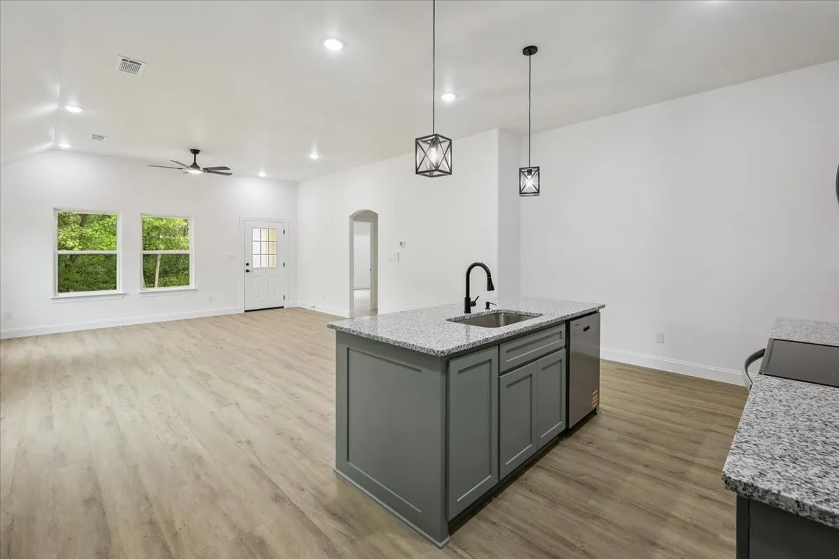 Kitchen with decorative light fixtures, arched walkways, gray cabinets, recessed lighting, and light stone counters