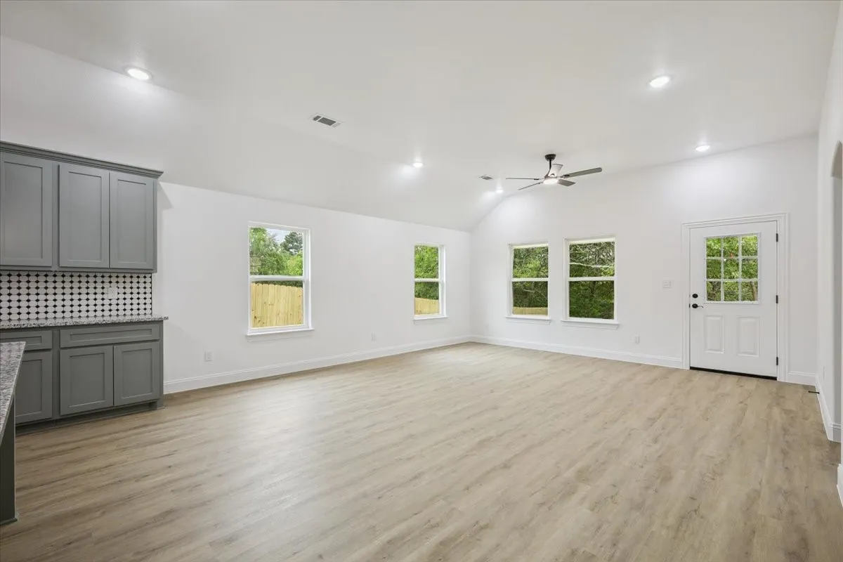 Unfurnished living room with light wood-type flooring, recessed lighting, vaulted ceiling, and ceiling fan