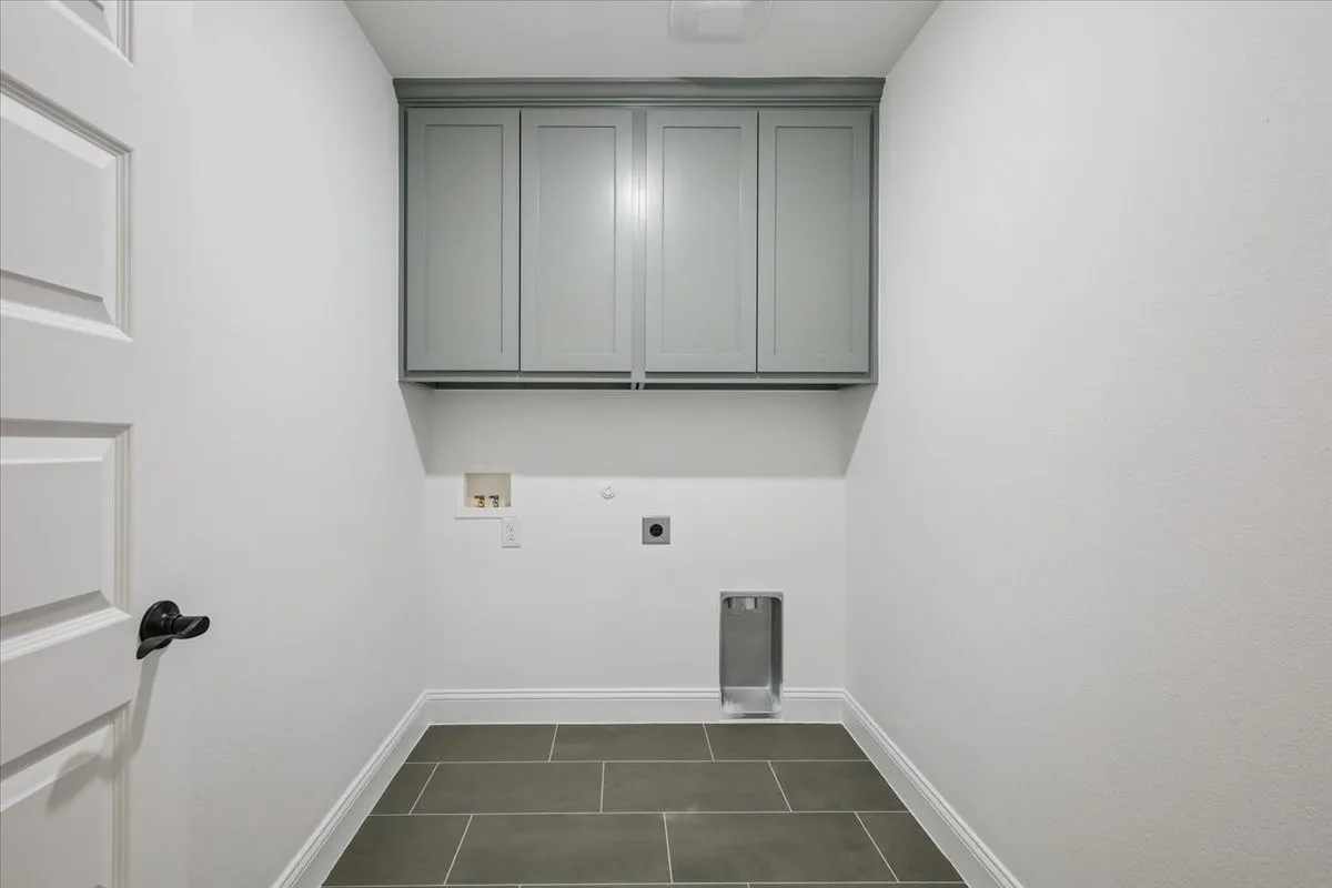 Laundry area with electric dryer hookup, cabinet space, hookup for a washing machine, dark tile patterned floors, and gas dryer hookup