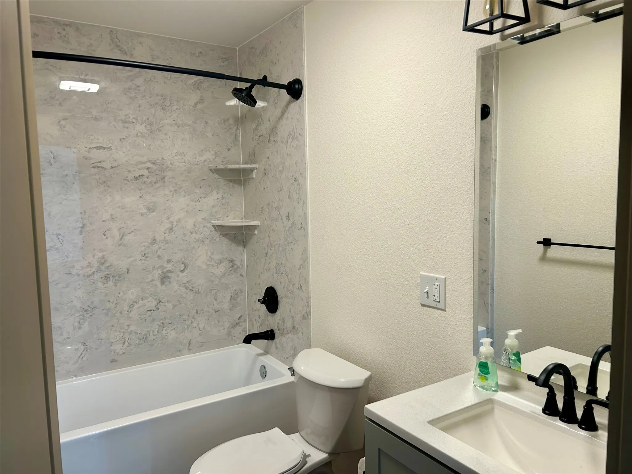 Bathroom featuring a textured wall, shower / tub combination, and vanity