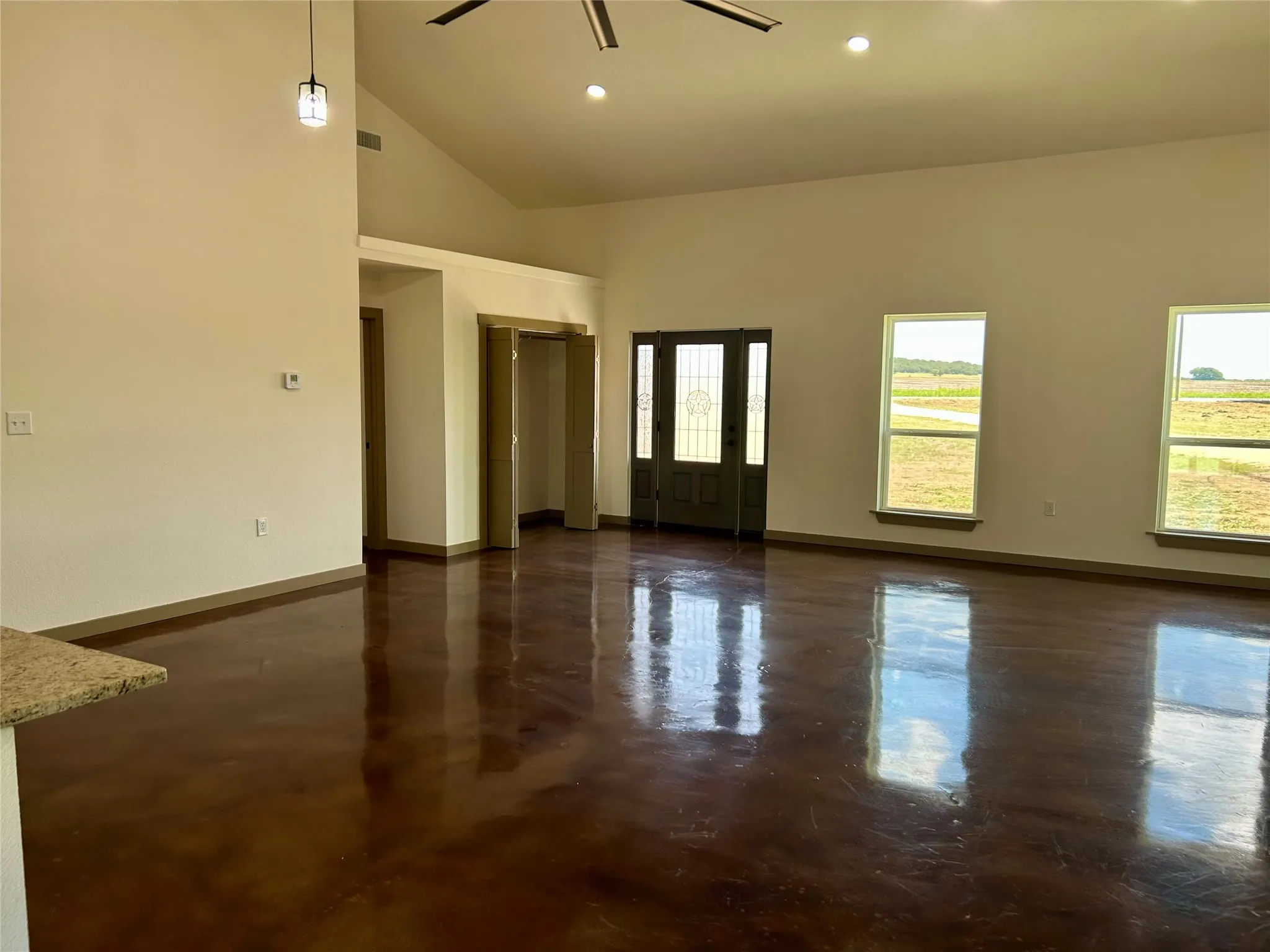 Spare room featuring finished concrete flooring, recessed lighting, a ceiling fan, and high vaulted ceiling