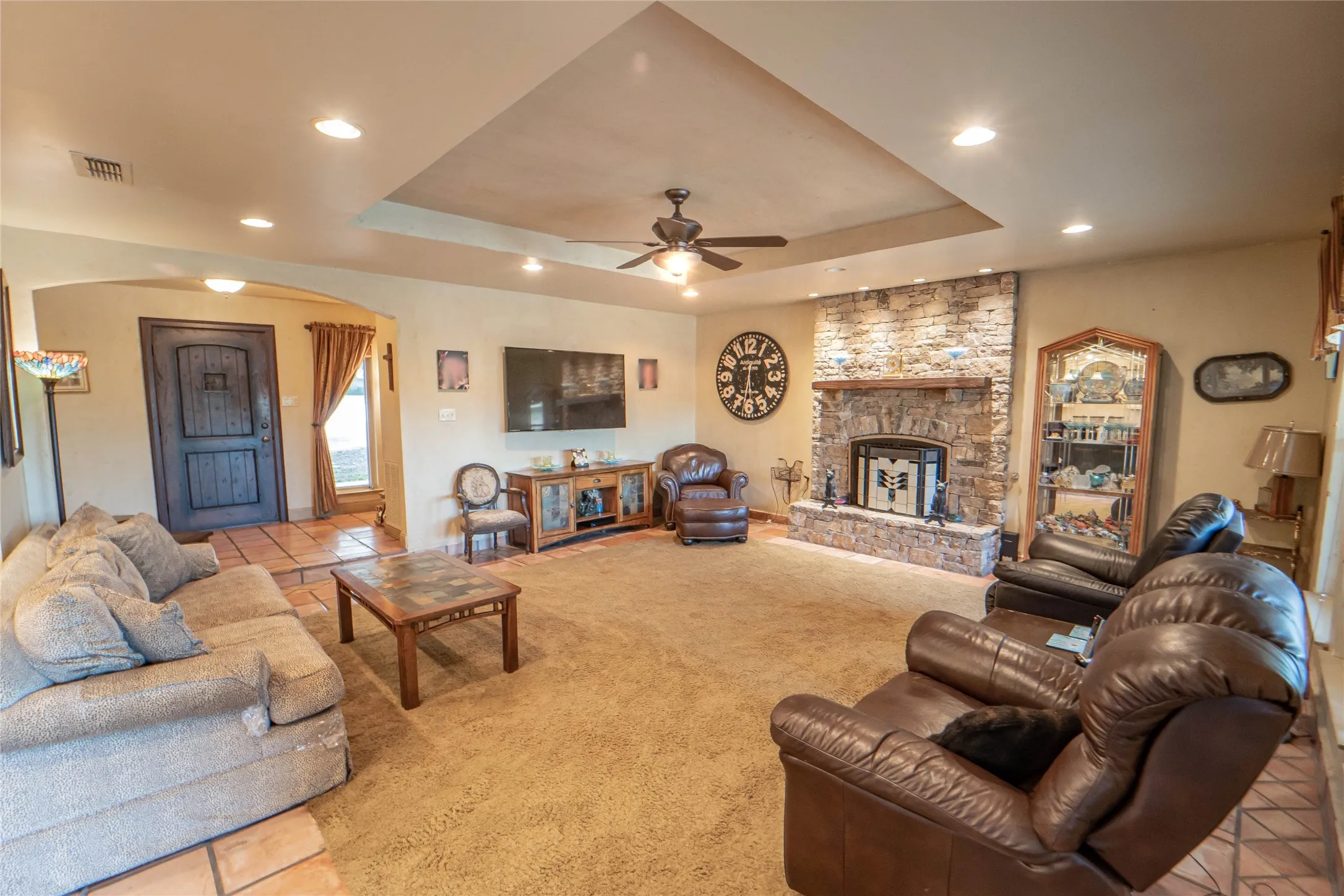 Main living area with cozy stone fireplace, tray ceiling and recessed lighting,is open to the kitchen and offers patio/pool access.