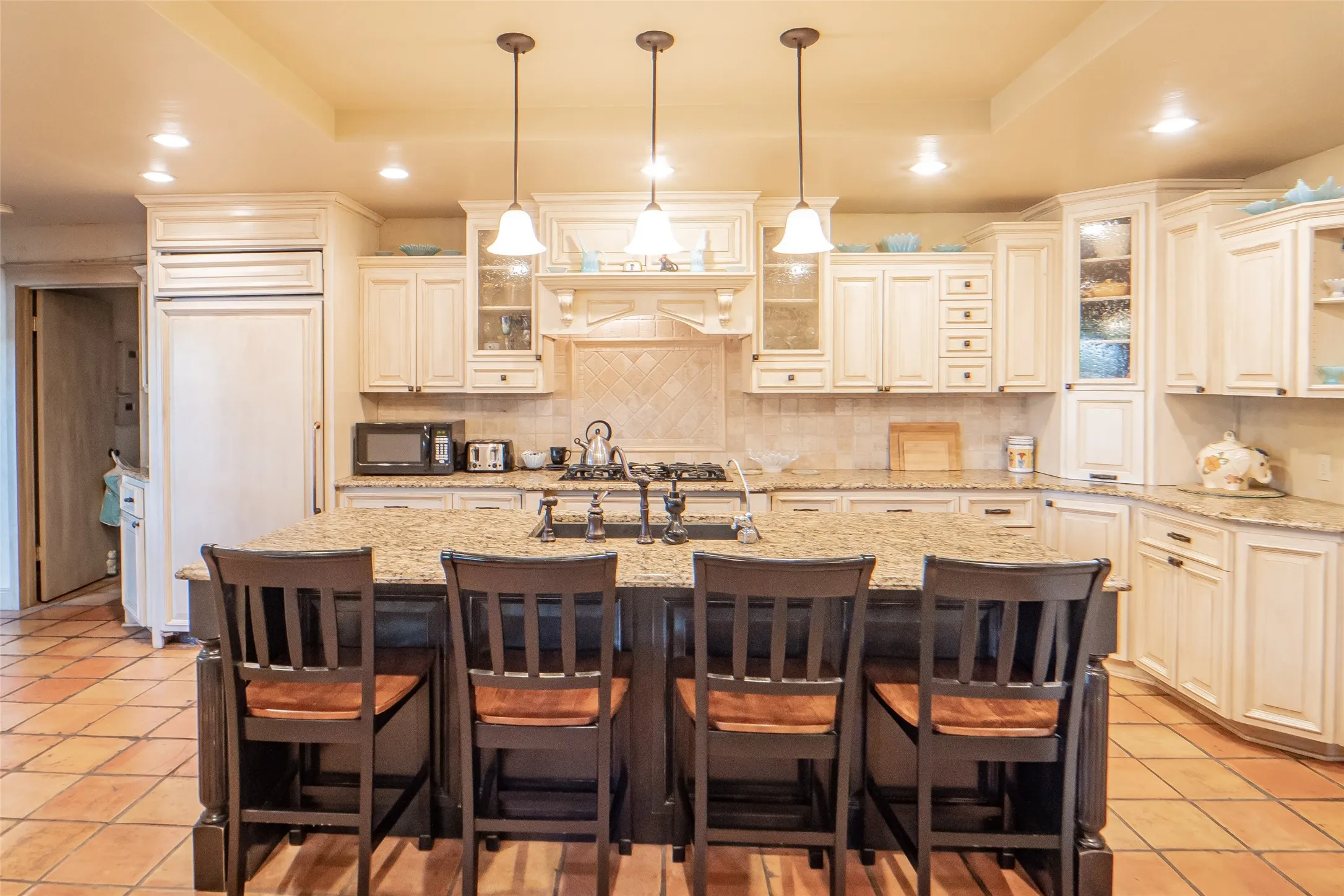Gourmet kitchen offers plenty of prep space with expansive island, granite counters and pendant lighting.