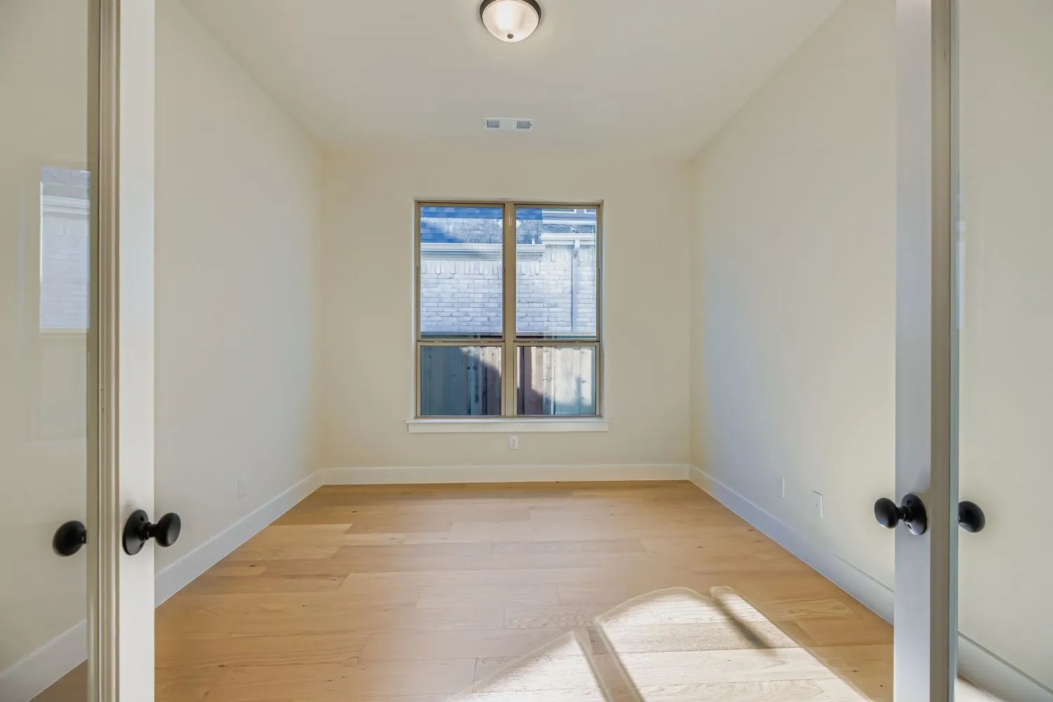 Unfurnished room with light wood-style floors and french doors