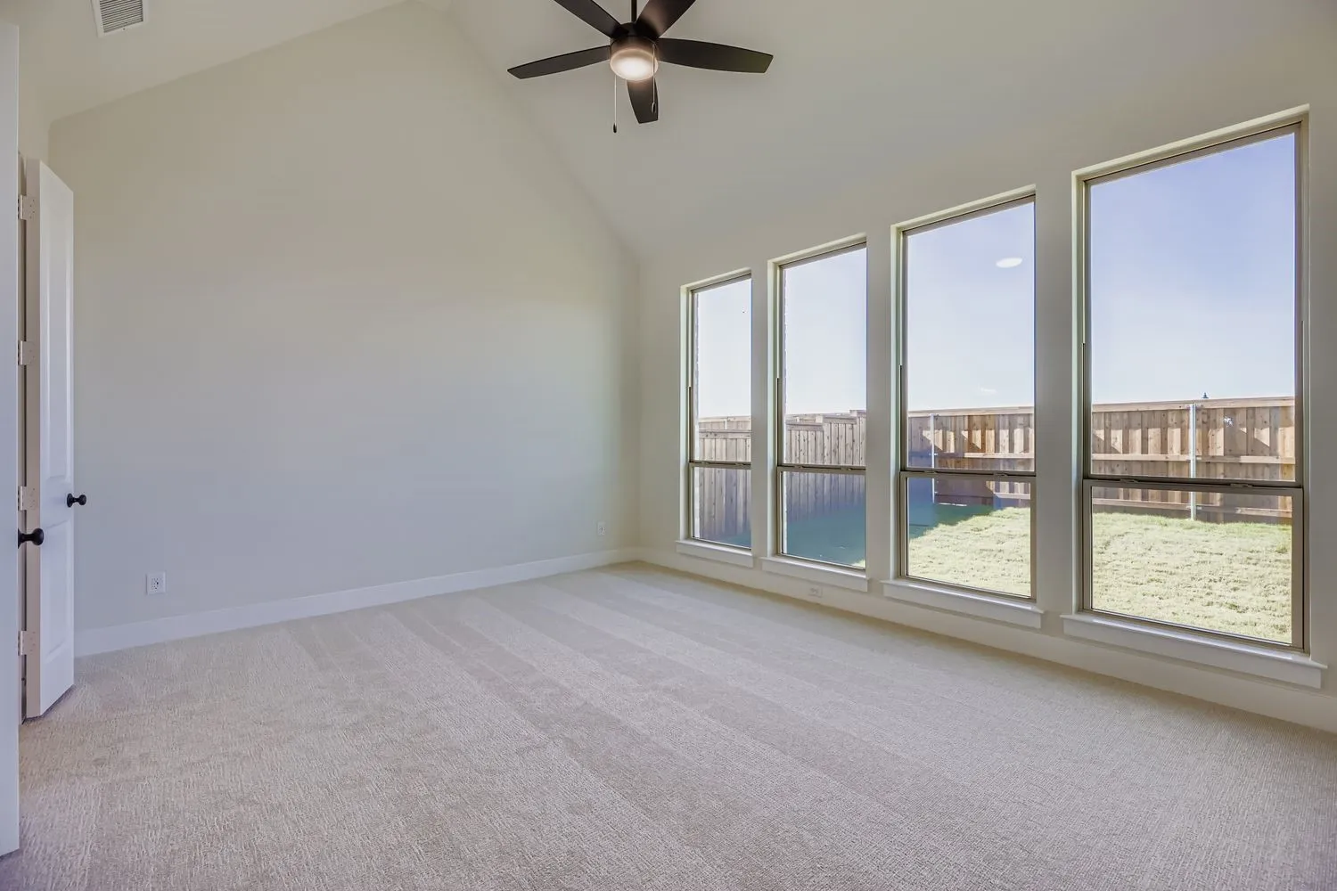 Spare room with high vaulted ceiling, light colored carpet, and ceiling fan