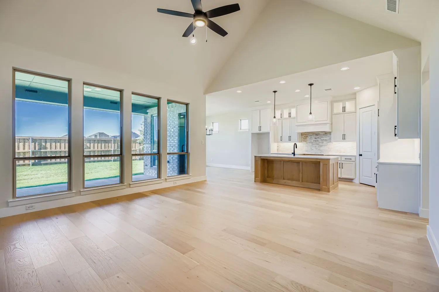 Unfurnished living room with high vaulted ceiling, light wood-style floors, recessed lighting, and a ceiling fan