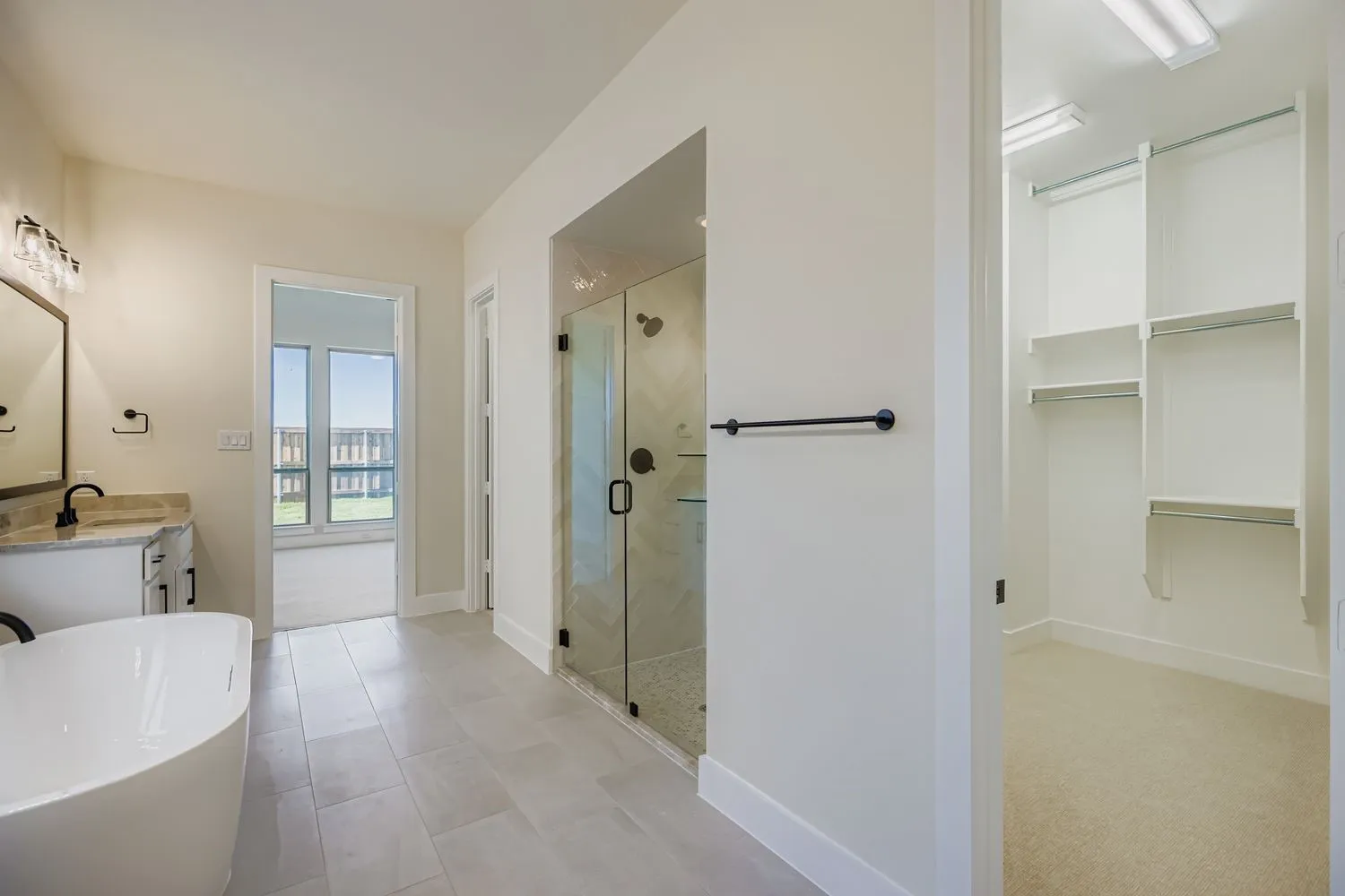 Bathroom with a freestanding tub, vanity, a stall shower, a walk in closet, and light carpet