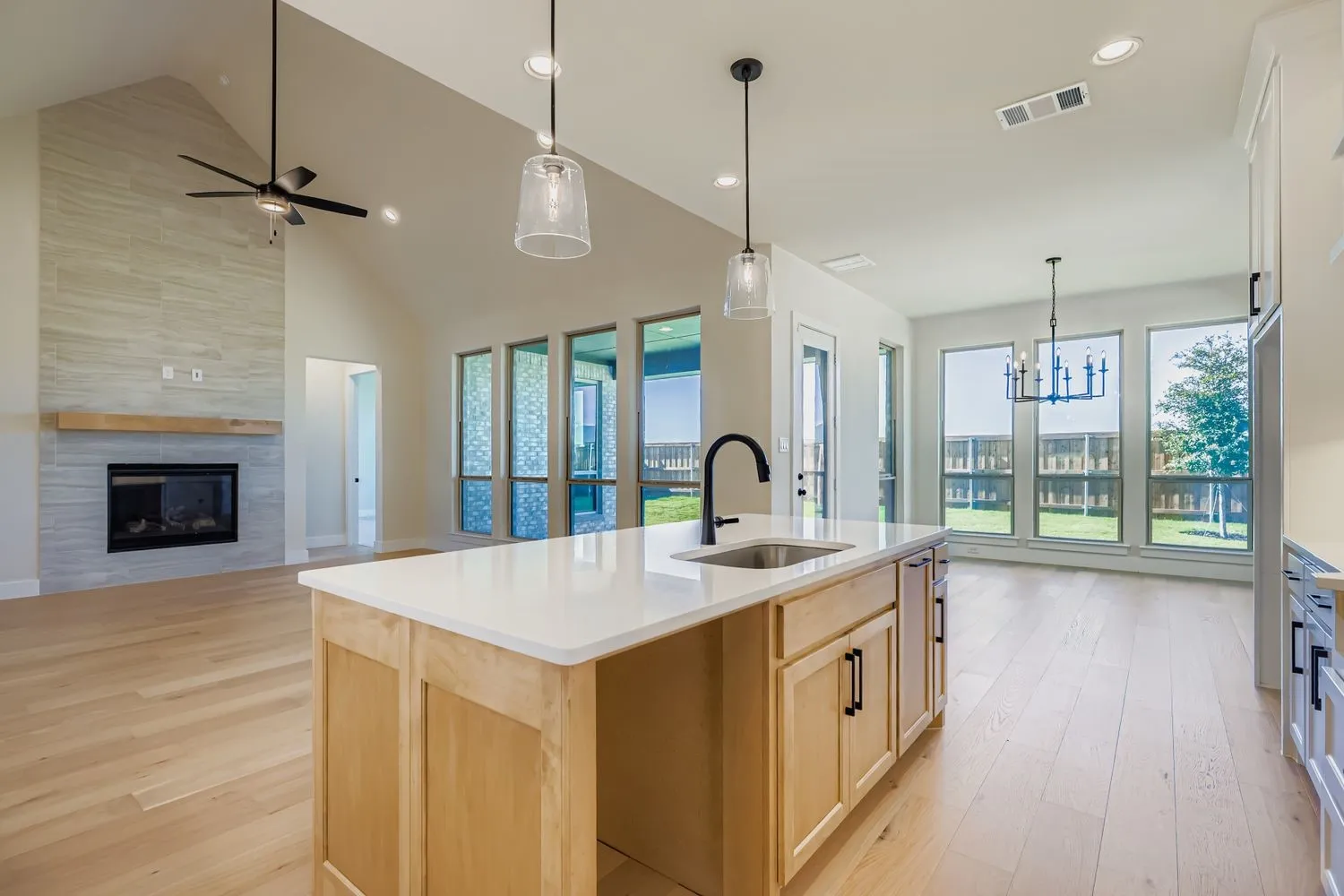 Kitchen featuring light brown cabinets, light wood-type flooring, hanging light fixtures, open floor plan, and plenty of natural light