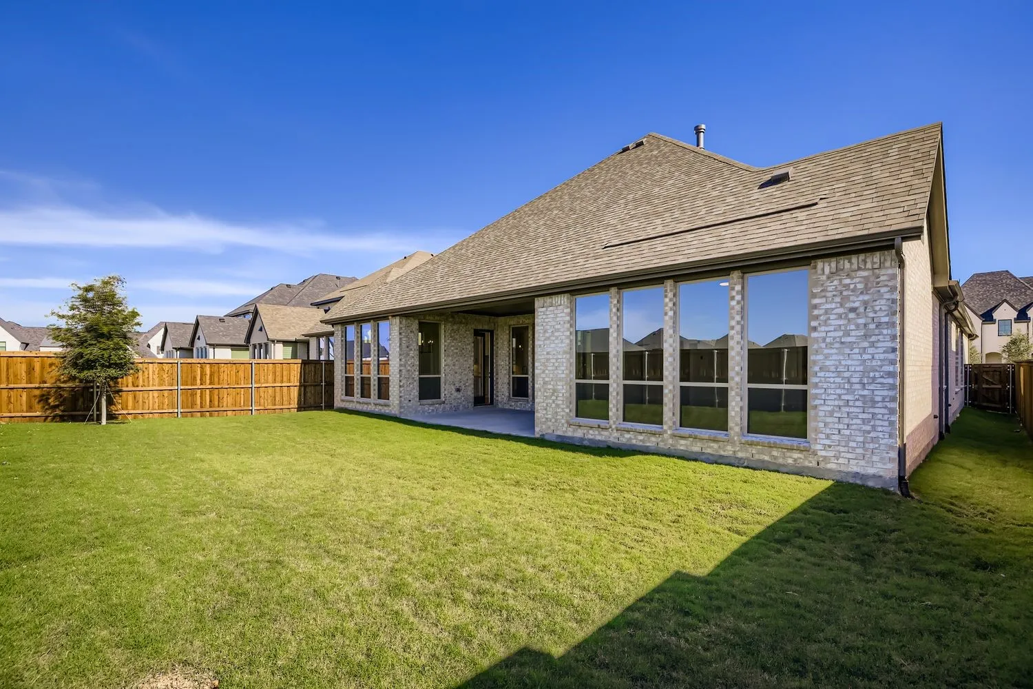 Back of house featuring brick siding, a patio, a shingled roof, and a fenced backyard