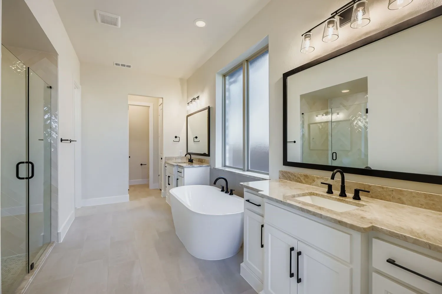Bathroom featuring two vanities, a freestanding bath, a stall shower, and recessed lighting