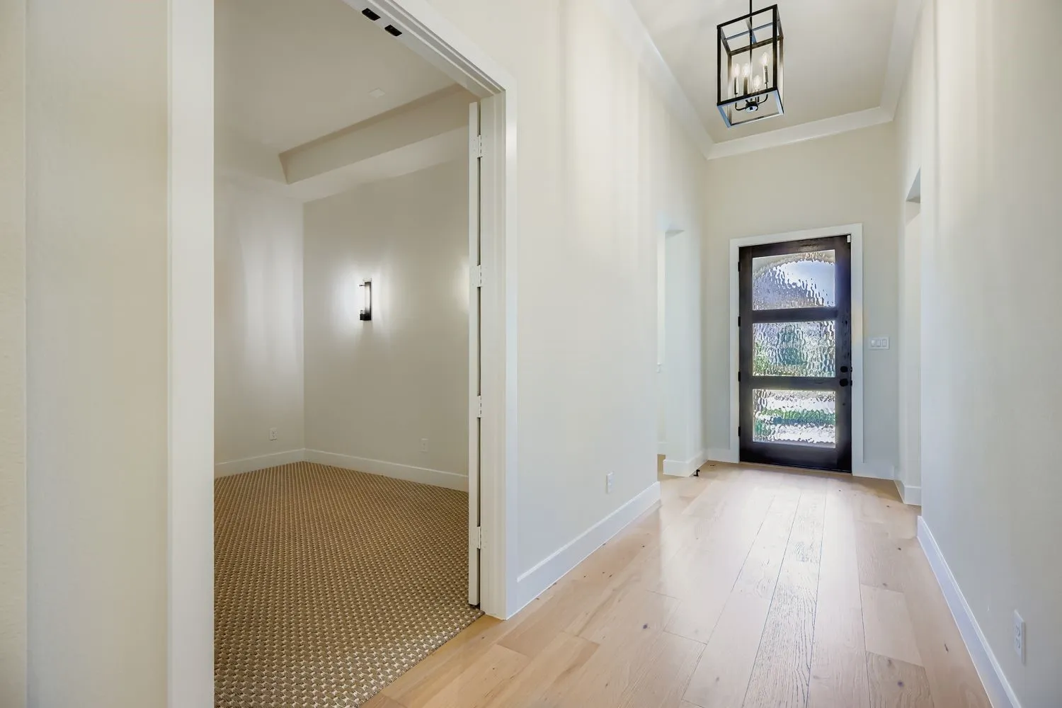 Entrance foyer with light wood-style flooring, crown molding, and a chandelier