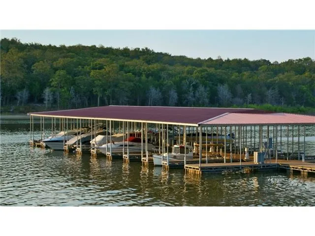 Dock featuring a water view, boat lift, and a forest view