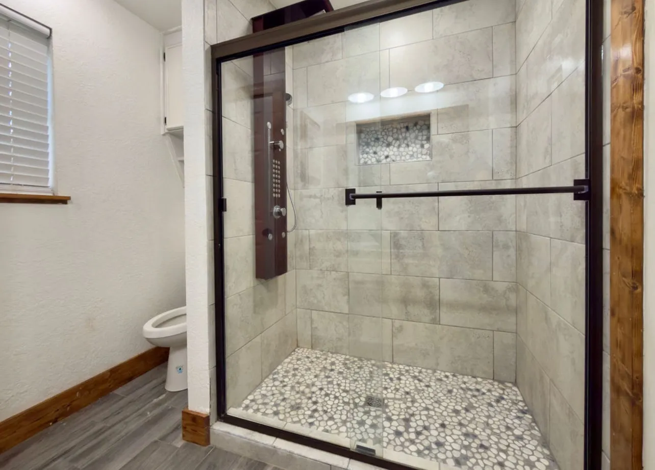 Bathroom with a stall shower, wood finished floors, and a textured wall