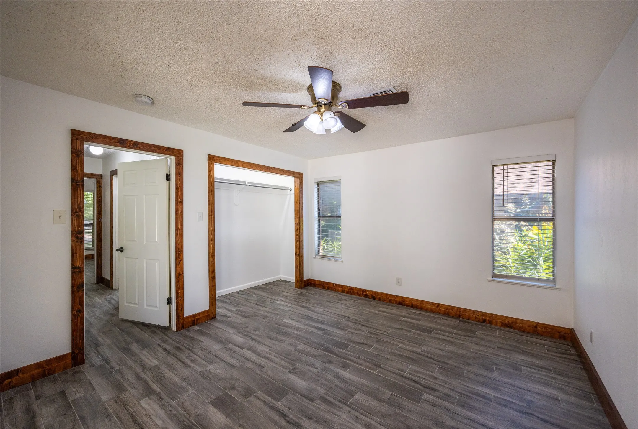 Unfurnished bedroom with a closet, a textured ceiling, dark wood-type flooring, and ceiling fan