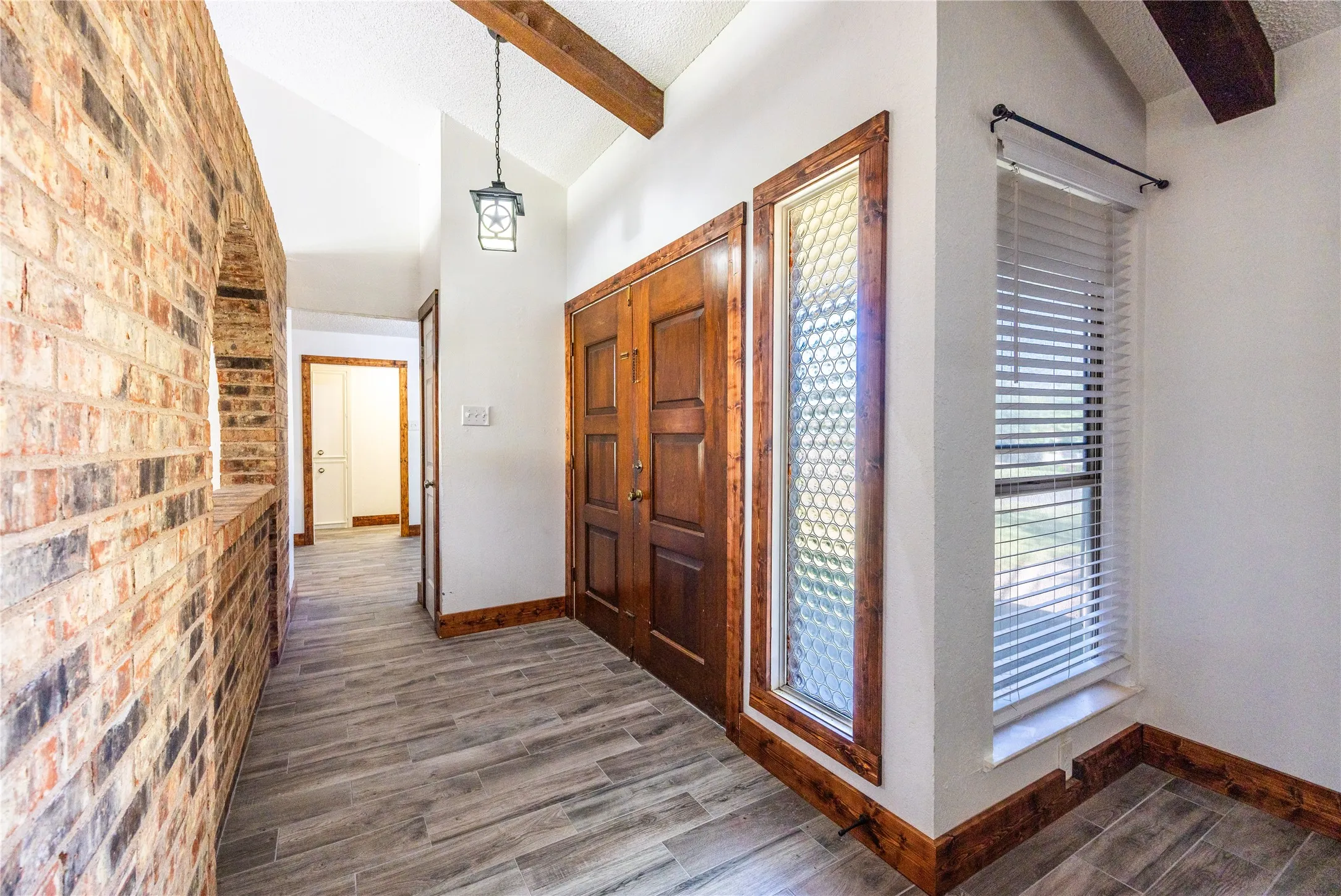 Foyer entrance with dark wood-type flooring and brick wall