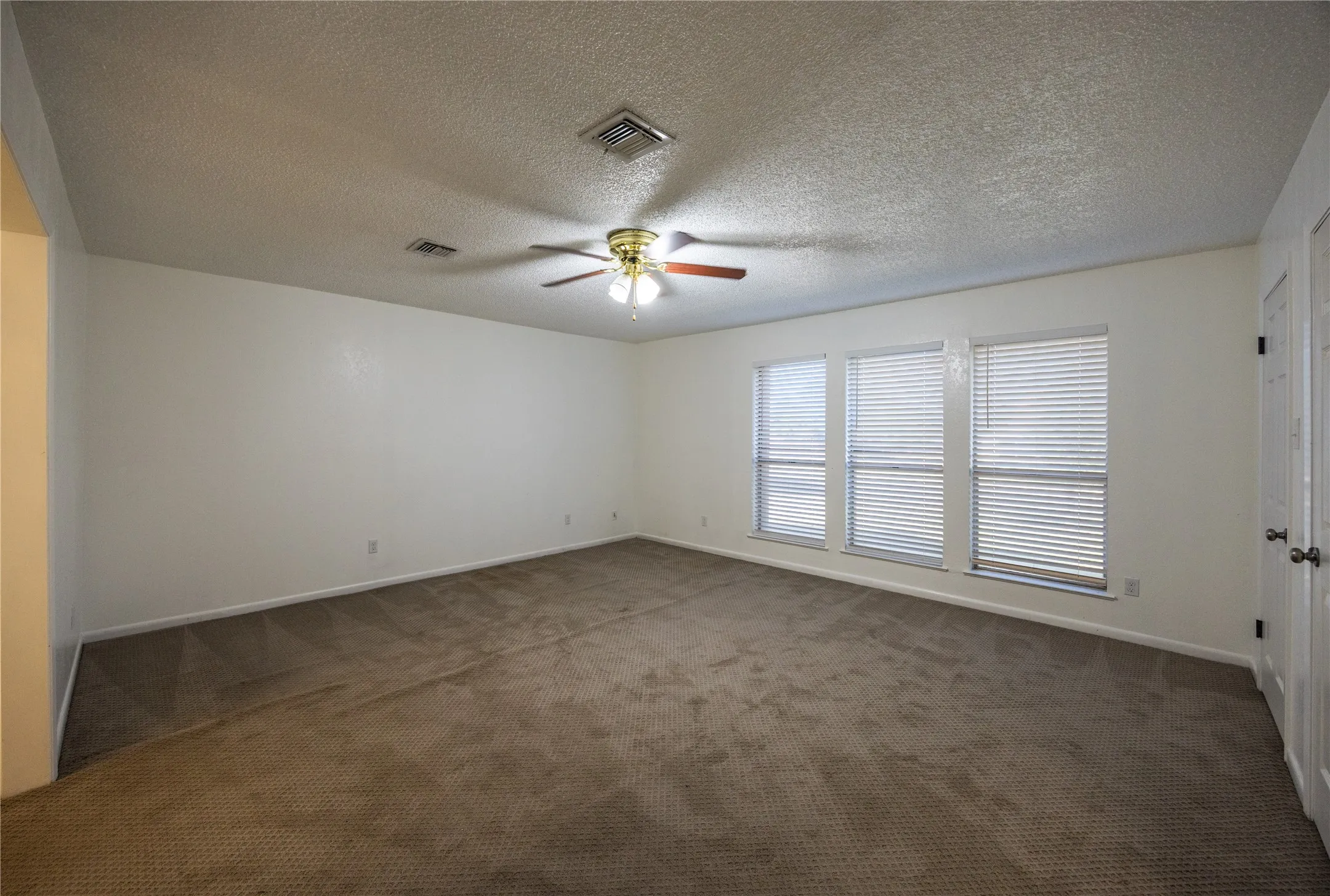 Spare room with dark colored carpet, a textured ceiling, and ceiling fan