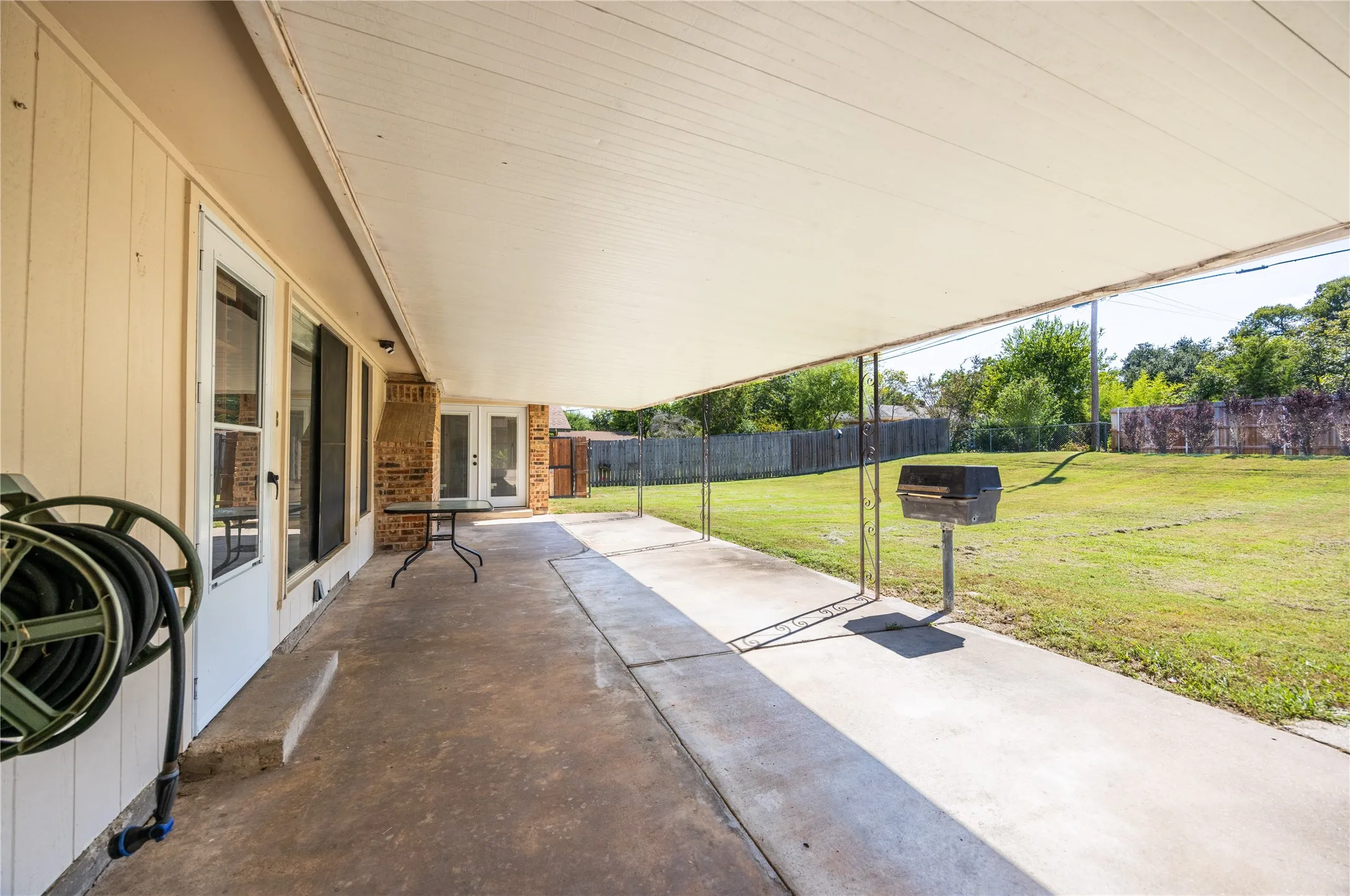 Fenced backyard featuring french doors and a patio