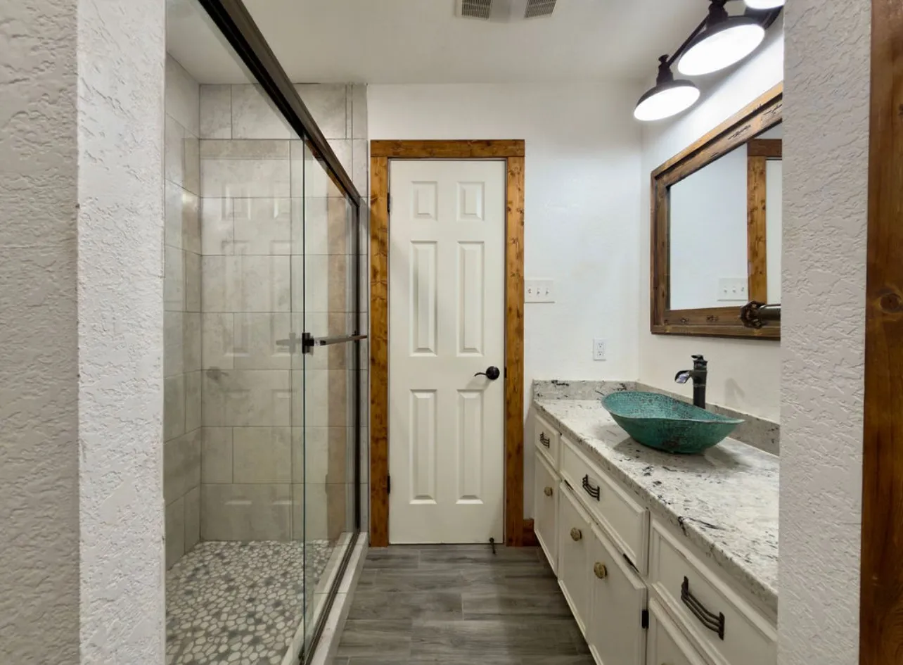 Full bathroom with vanity, a stall shower, a textured wall, and dark wood finished floors
