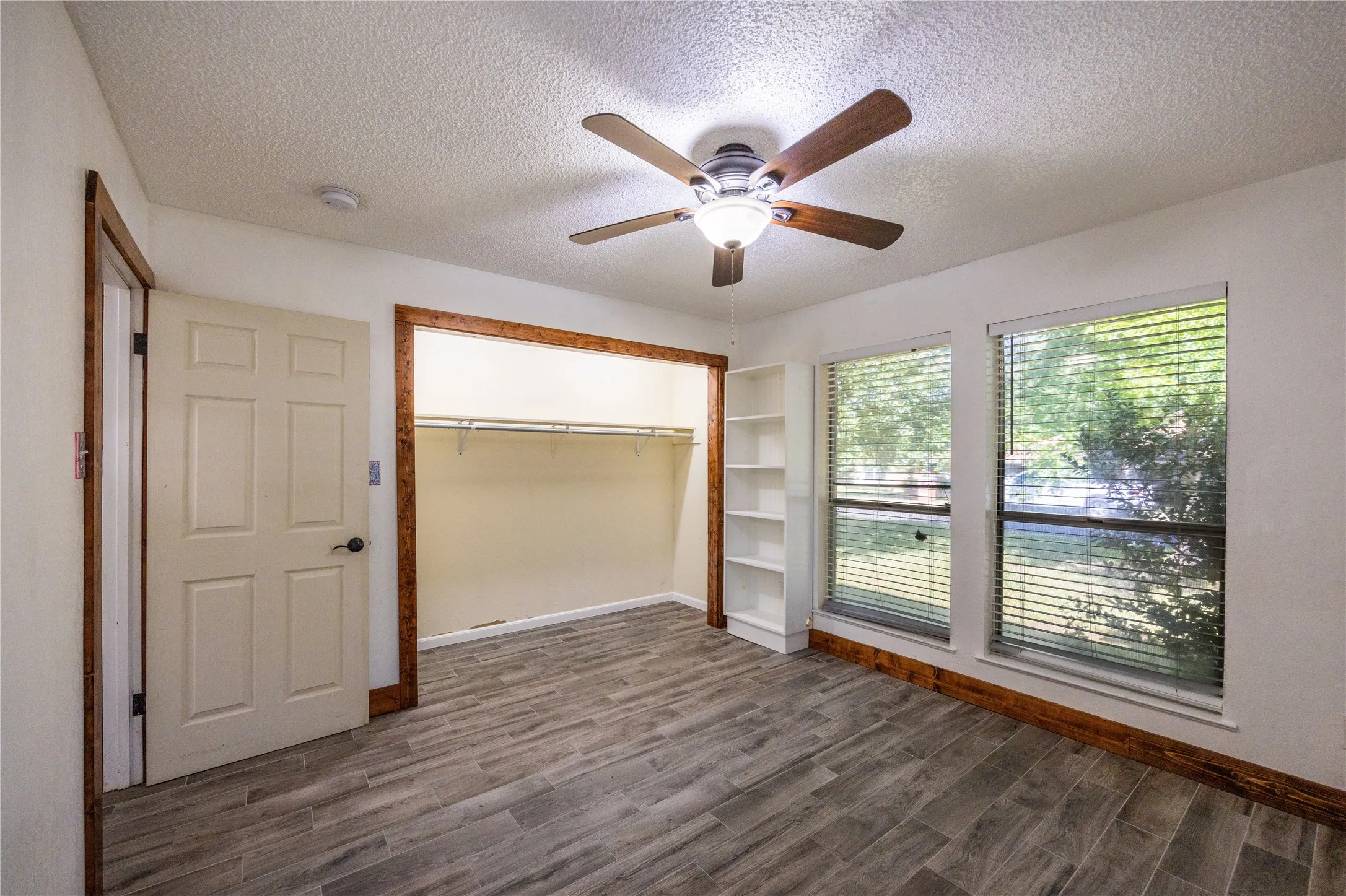 Unfurnished bedroom with a textured ceiling, dark wood-style flooring, a ceiling fan, and a closet